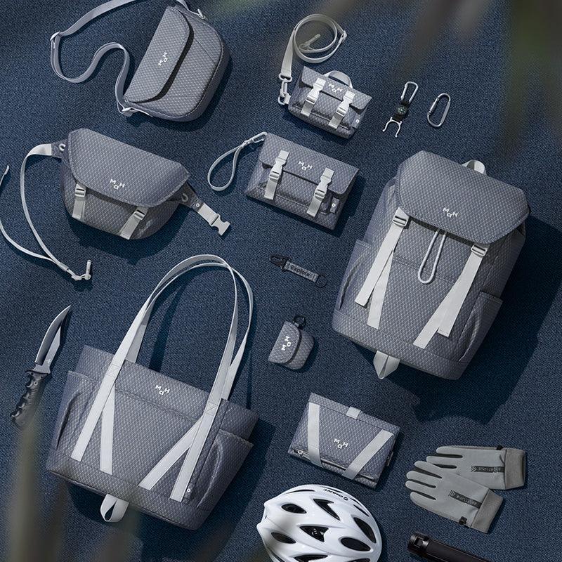 Grey textured backpacks, totes, and accessories with white straps, styled for urban lifestyle and travel.