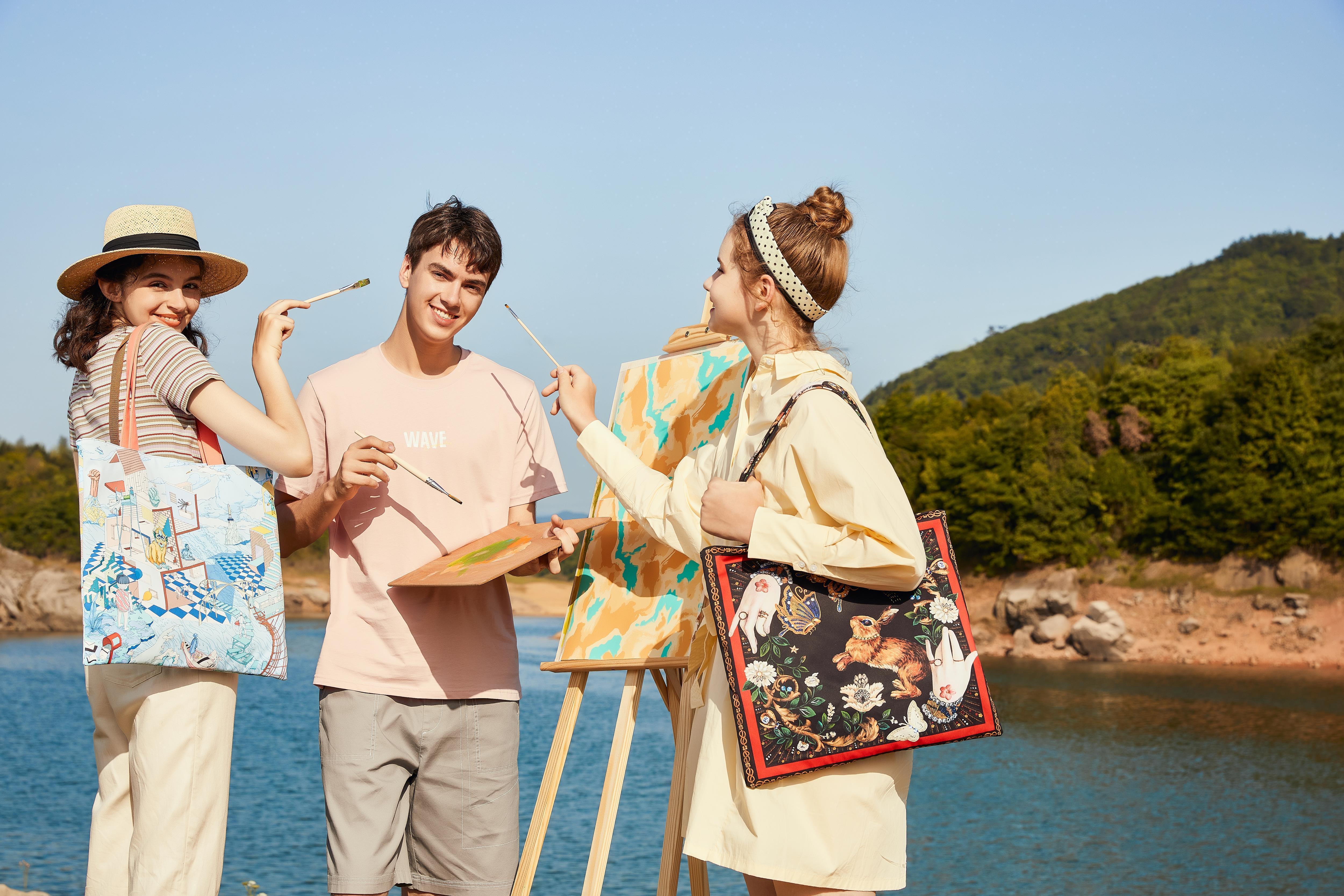 Artists painting by lake with stylish printed tote bags, perfect for creative lifestyle and outdoor adventures.