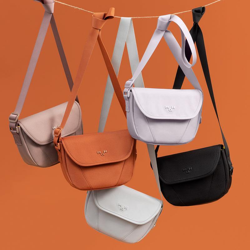 Stylish crossbody bags in multiple colors hanging on a line, perfect for everyday use and travel.