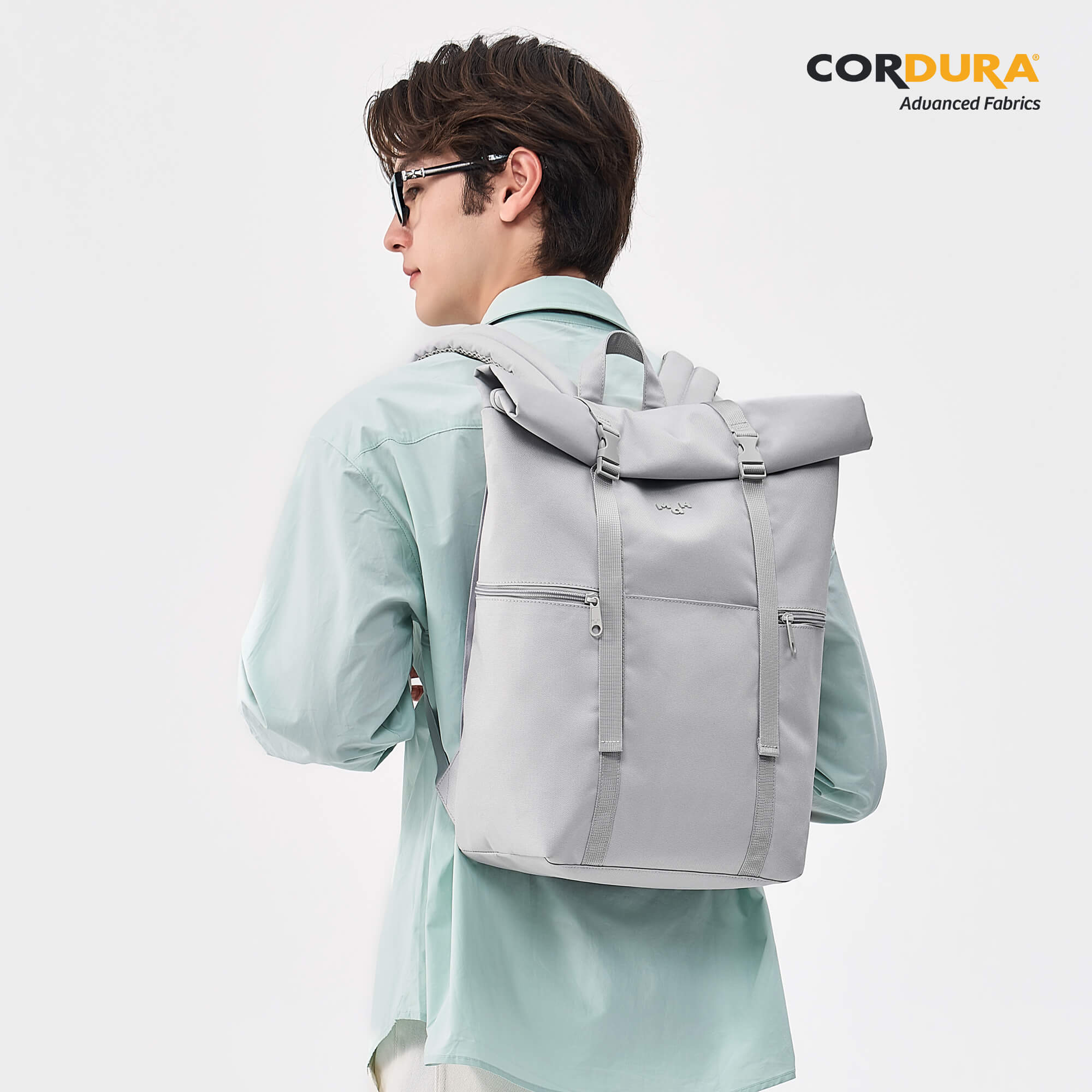 Gray roll-top backpack with Cordura fabric, worn by man in light blue shirt