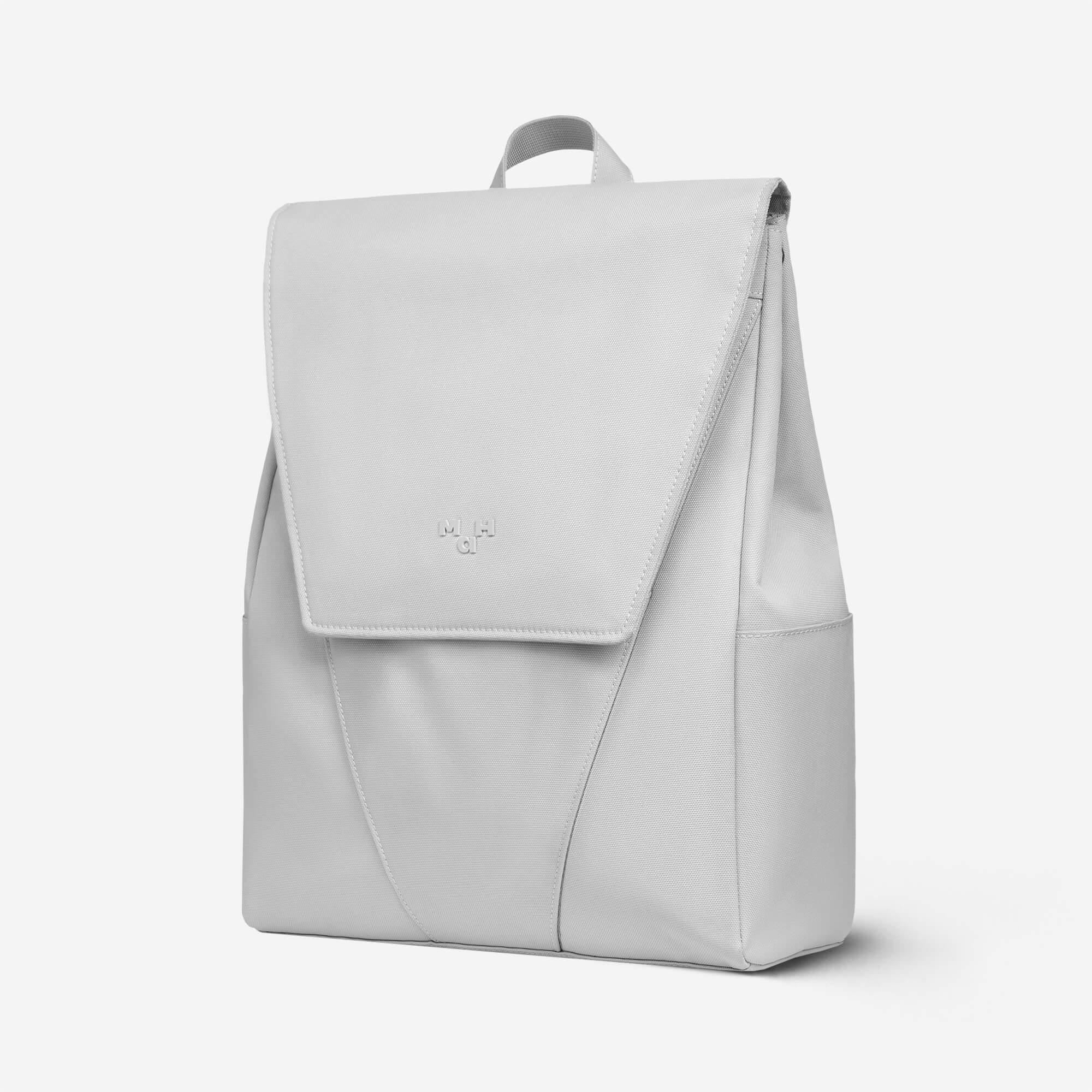 Light gray minimalist backpack with flap closure and subtle logo, ideal for daily use or travel