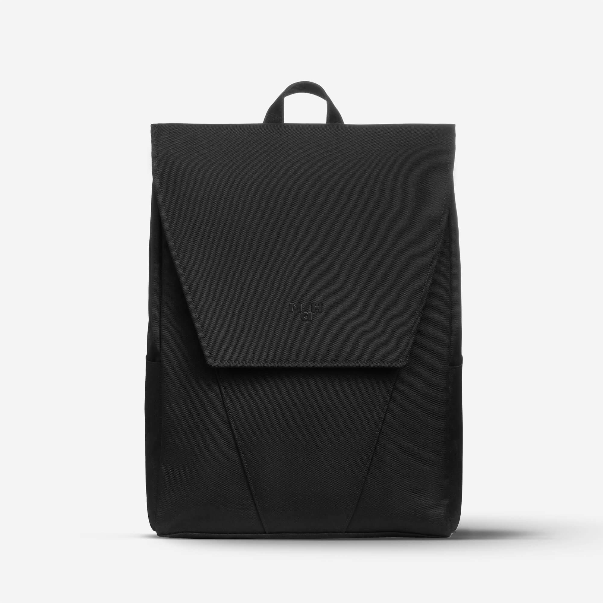 Black minimalist backpack with flap closure and subtle logo, ideal for everyday carry and urban style.