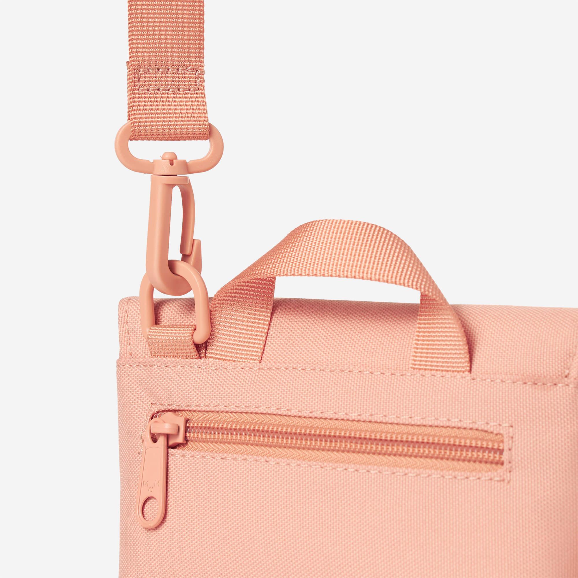 Pink canvas bag with adjustable strap, top handle, and front zipper pocket for everyday carry