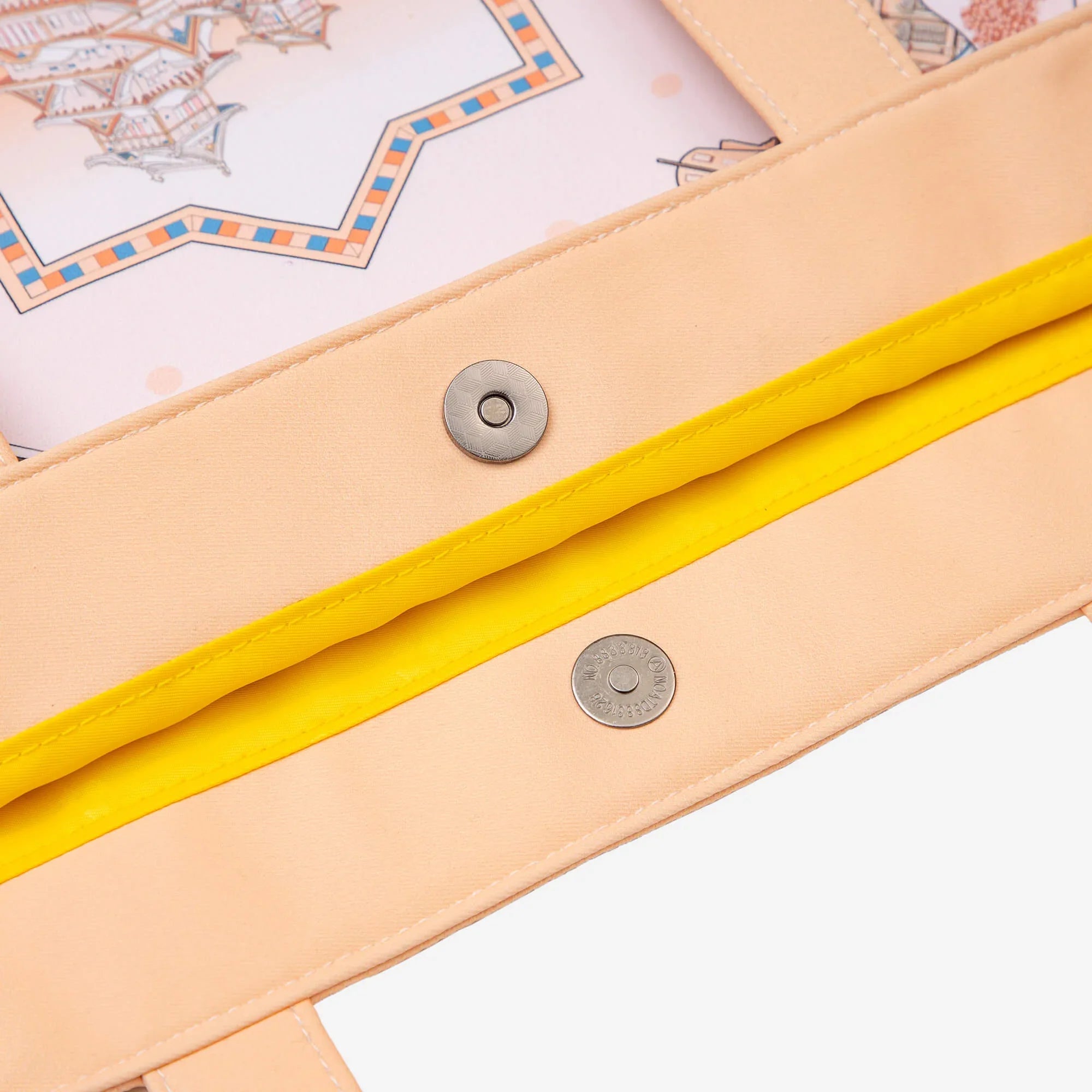 Peach tote bag with yellow strap and metal snap closures, featuring illustrated map design