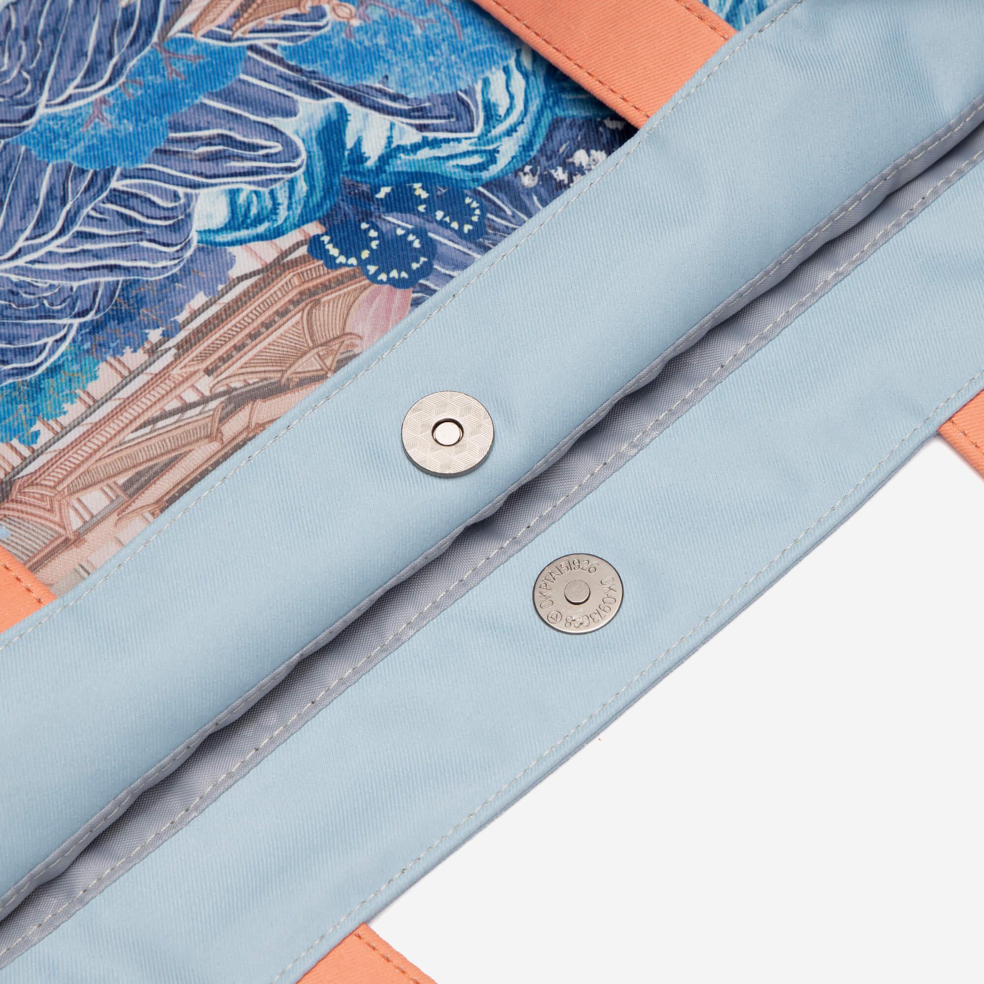 Light blue bag with blue floral print, orange trim, and metal snap closures