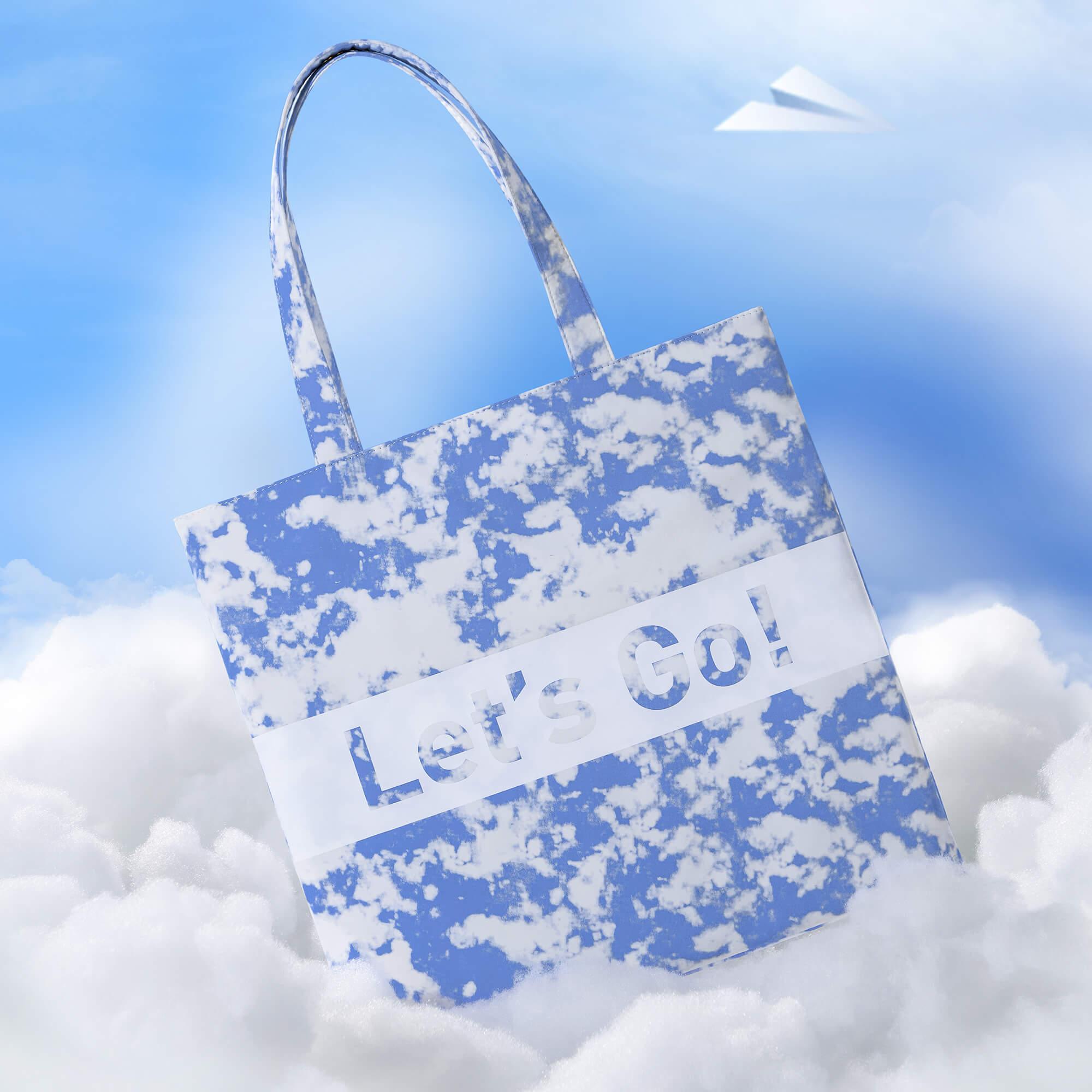 Cloud-print tote bag with 'Let's Go!' text, sky background, paper airplane
