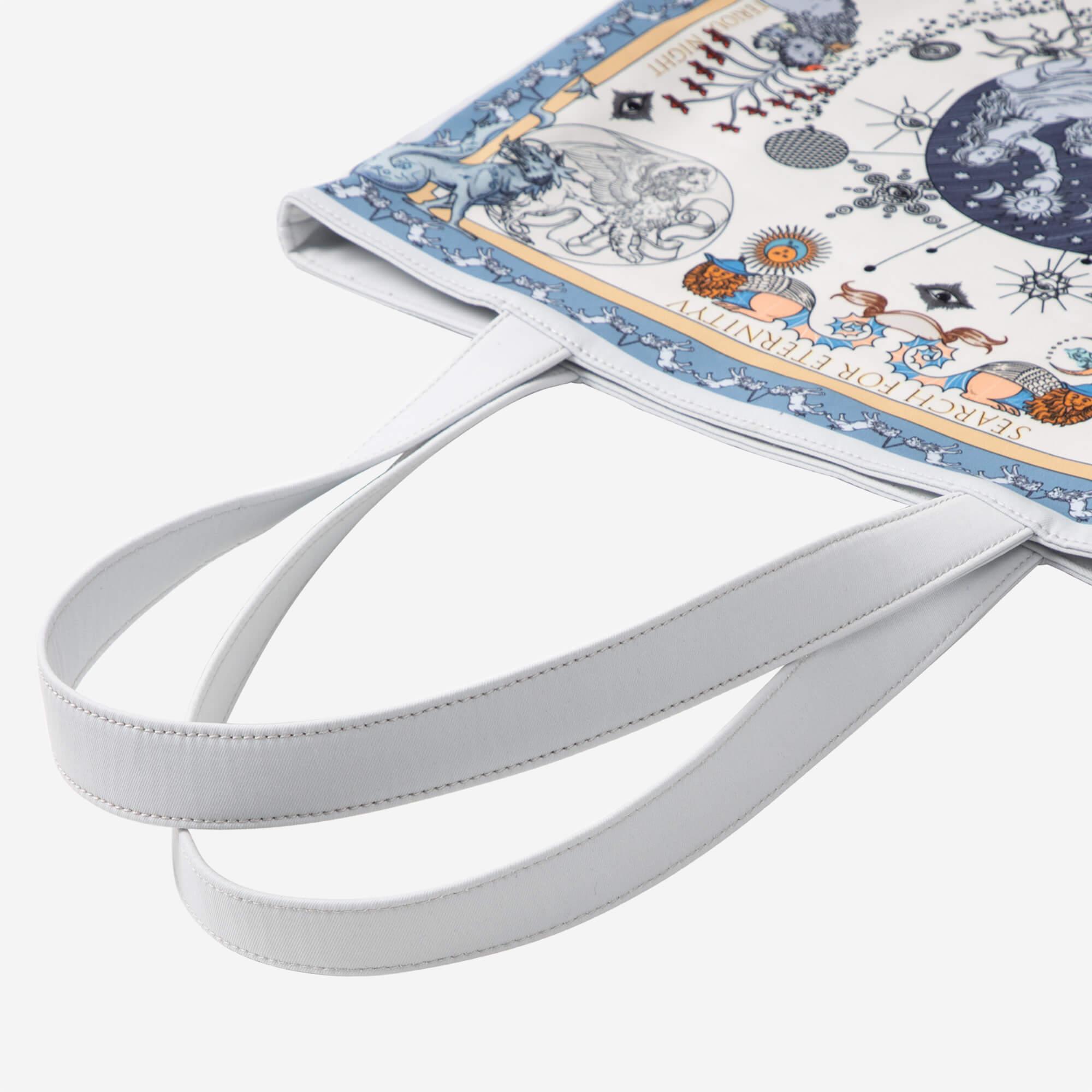 White tote bag with celestial and mythological print, featuring stars, moons, and fantasy creatures
