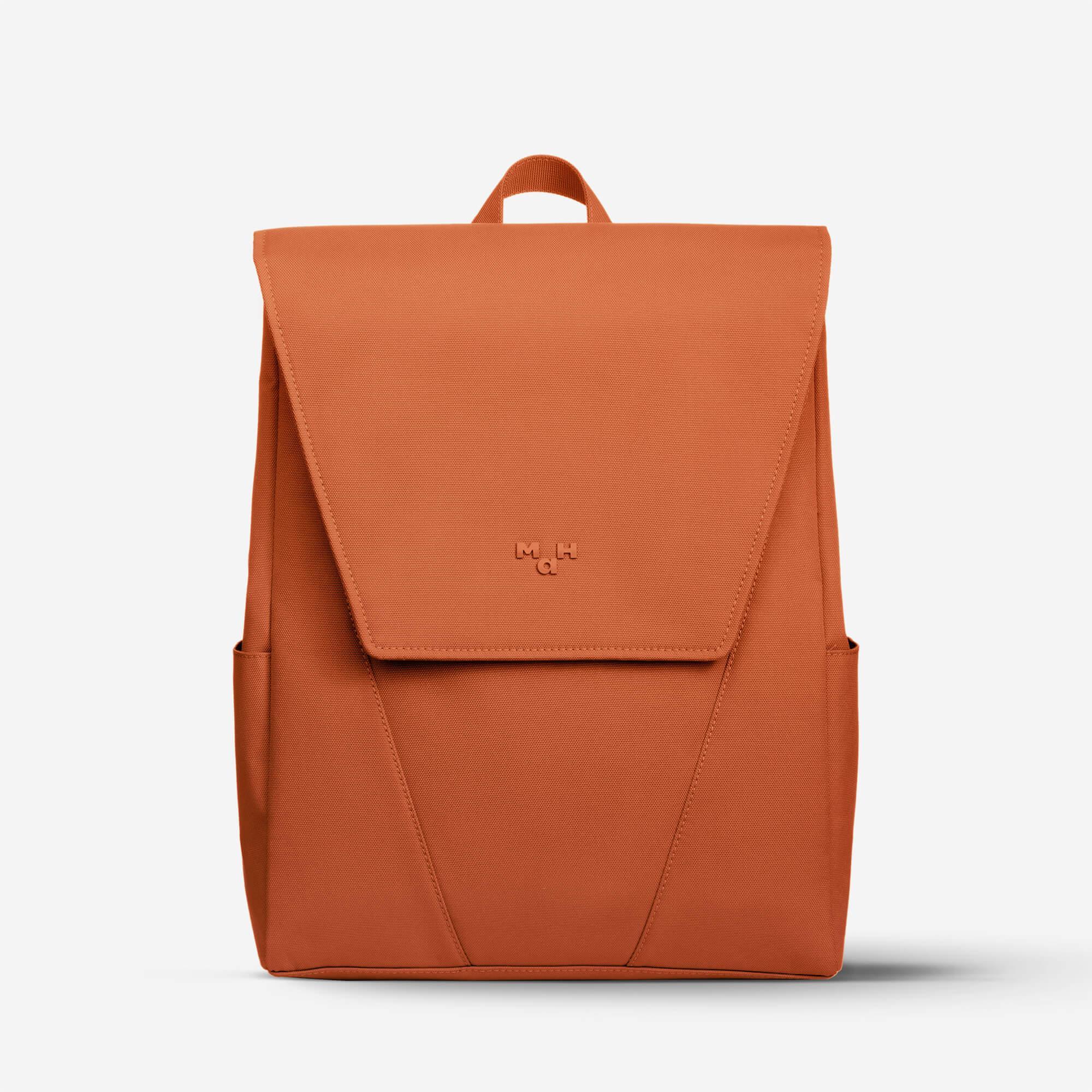 Rust-colored minimalist backpack with front flap and side pockets, ideal for daily use or travel