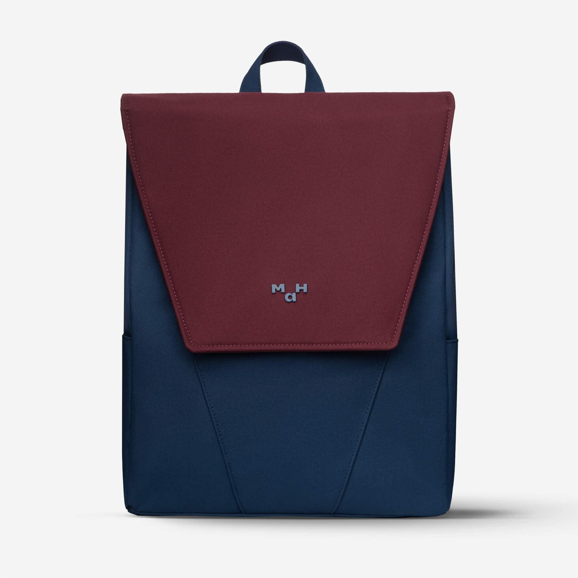 Maroon and navy blue backpack with flap closure and minimalist logo, ideal for daily use or travel.