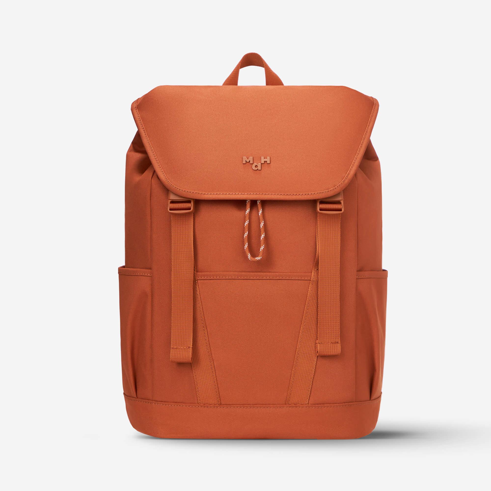 Rust orange backpack with front flap, side pockets, and drawstring closure, ideal for daily use or travel.