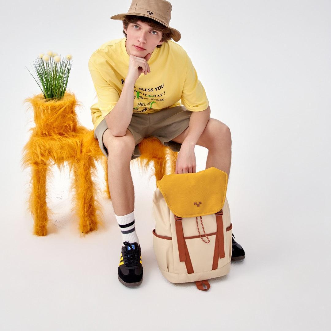 Yellow and beige backpack with brown straps, styled with casual outfit and fuzzy chair