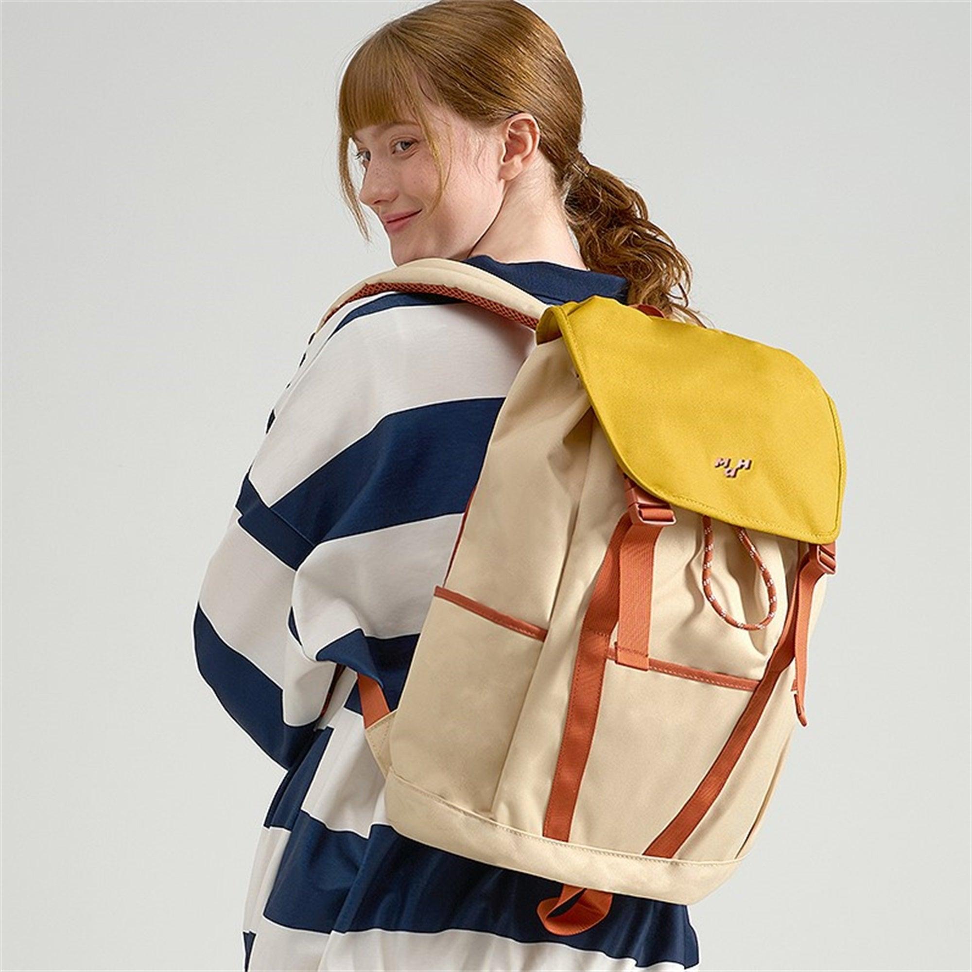 Woman wearing beige and yellow canvas backpack with brown straps, ideal for school or travel