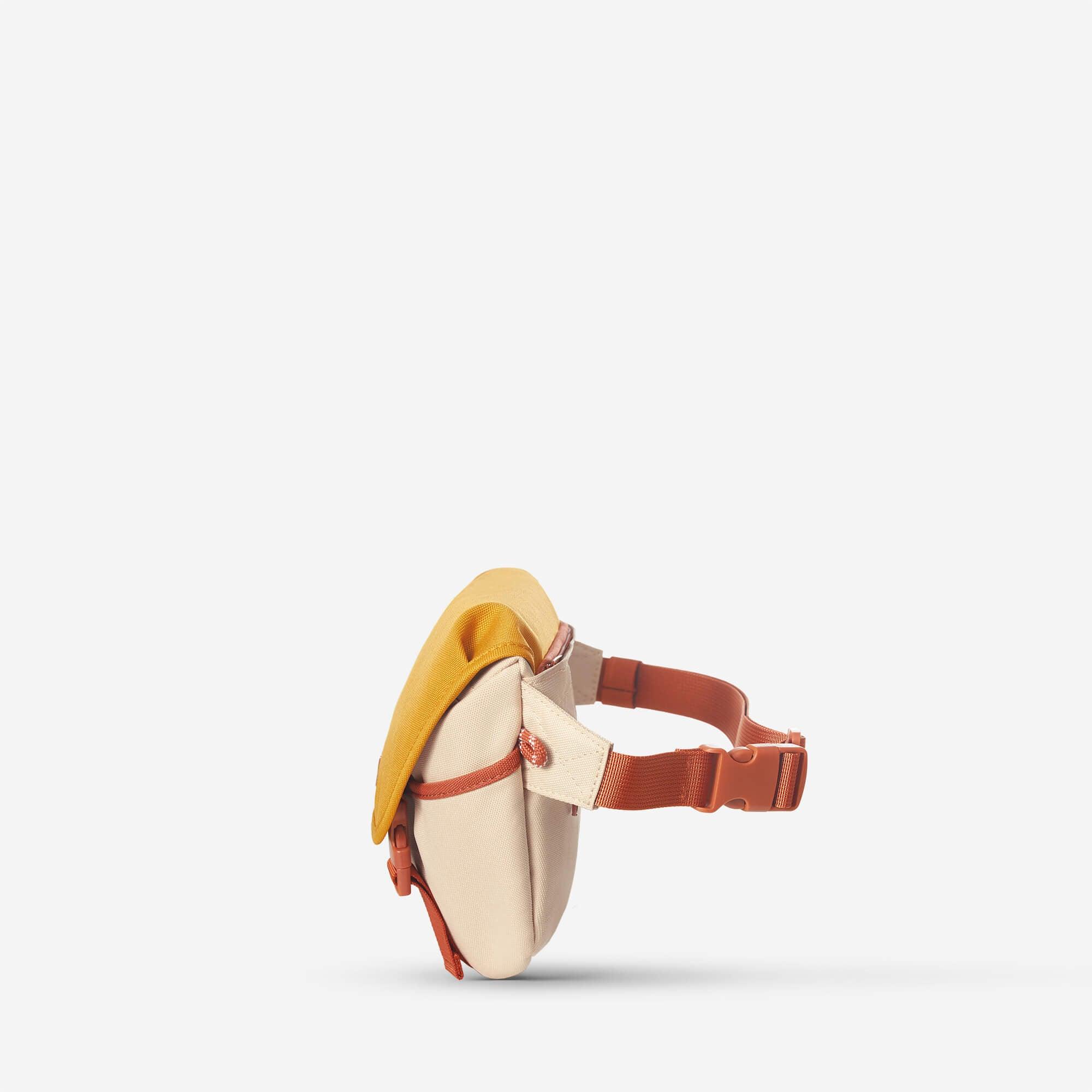 Compact beige and mustard waist bag with adjustable orange strap, ideal for travel or daily use.