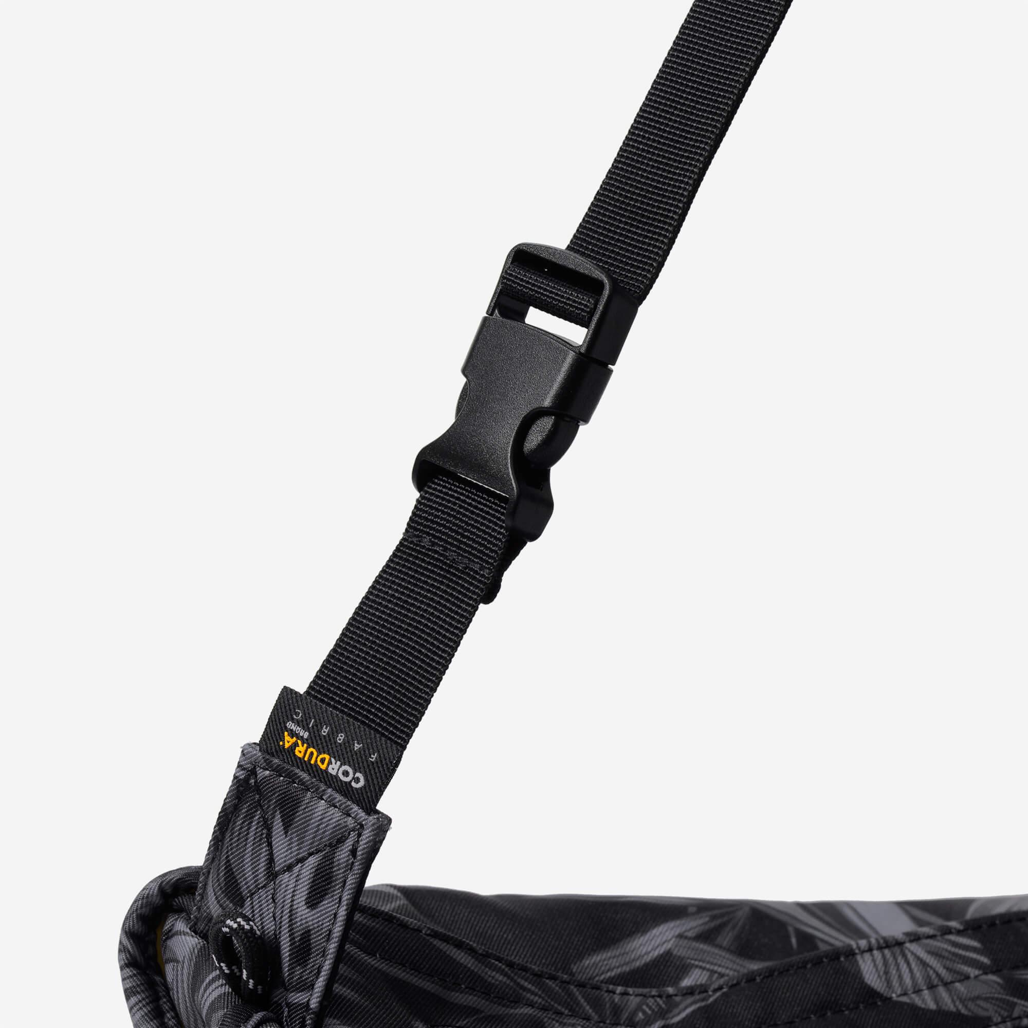 Black adjustable strap with buckle on patterned bag, featuring Cordura fabric label for durability.