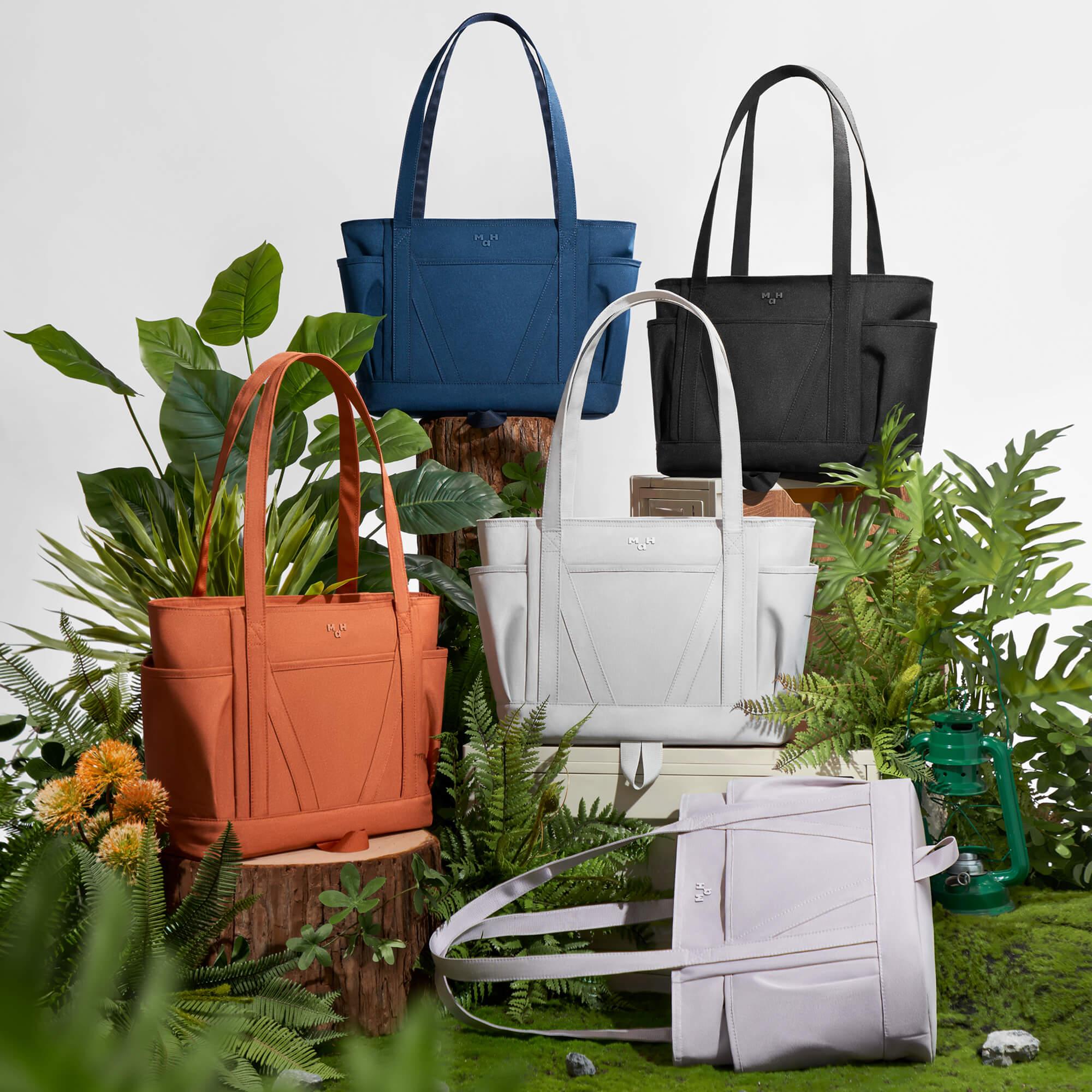 Stylish tote bags in blue, black, white, orange, and pink, displayed with green plants and moss for a natural, lifestyle look.