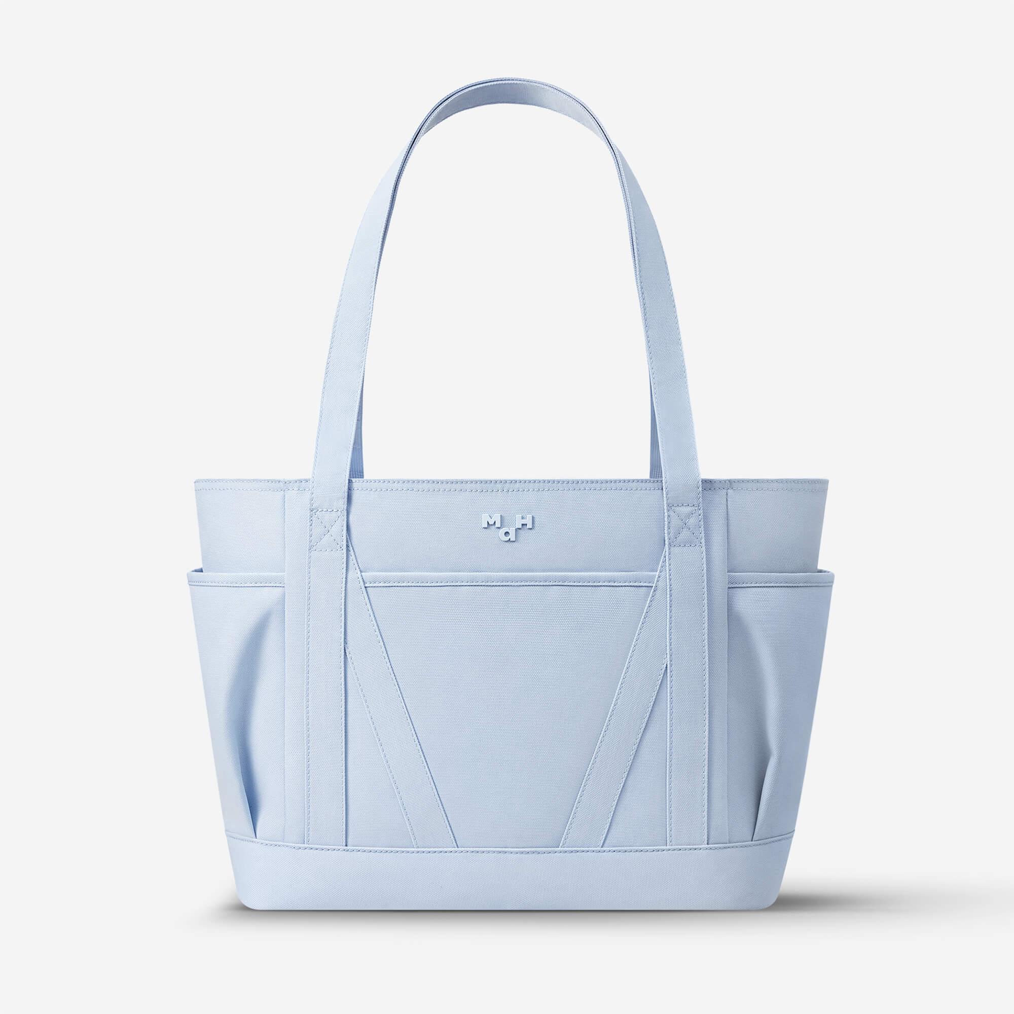 Light blue structured tote bag with dual handles and front pockets, ideal for everyday carry and lifestyle use.