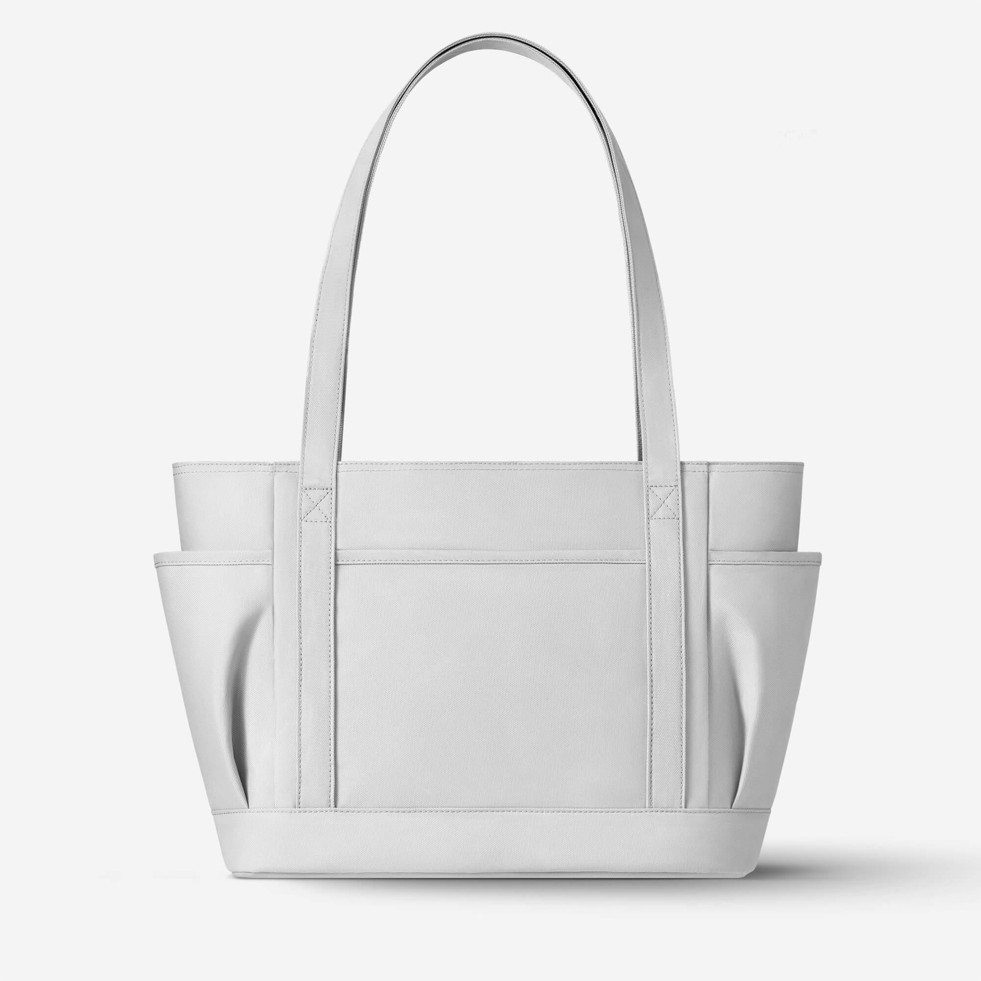 Light gray canvas tote bag with side pockets and sturdy handles, ideal for everyday use or shopping.