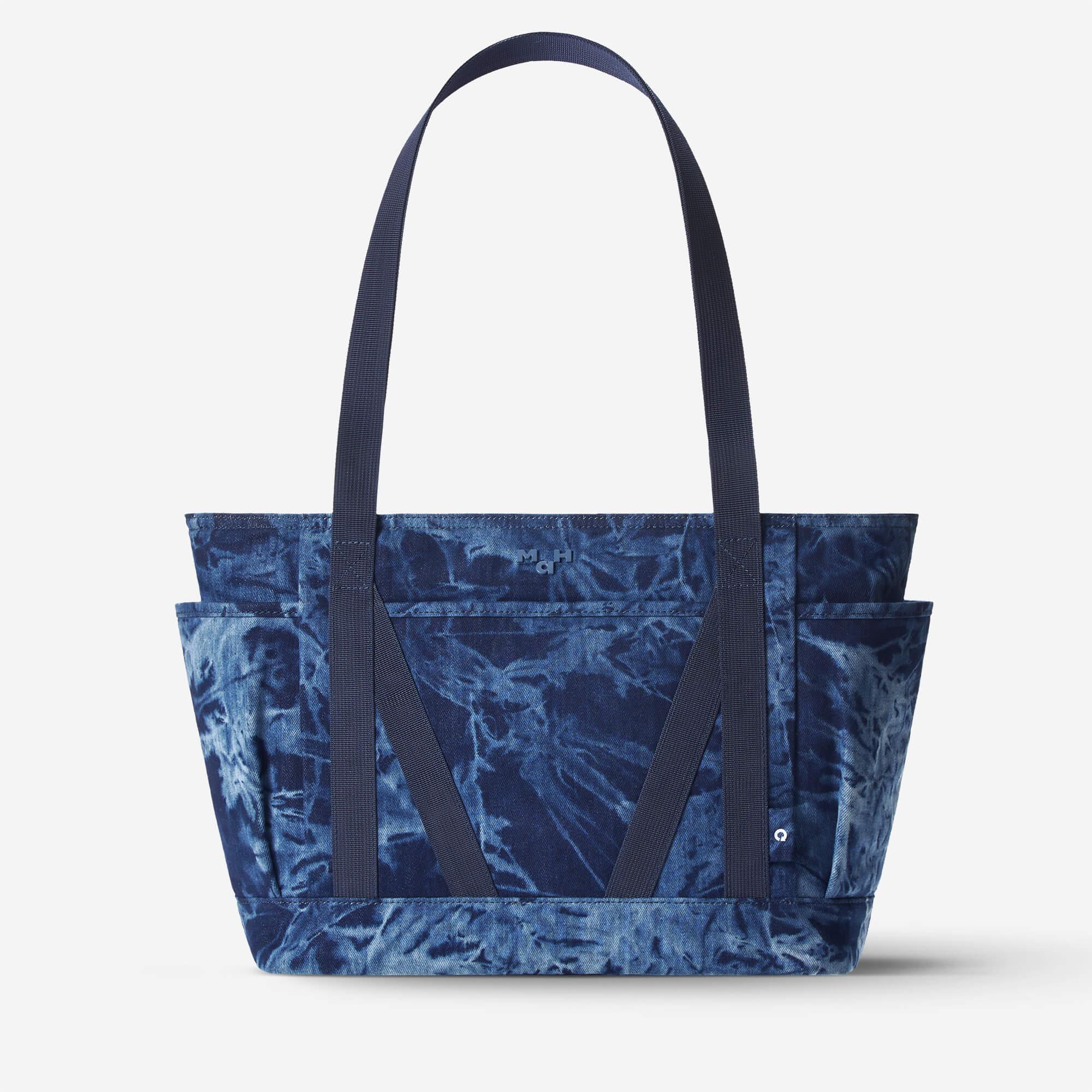 Blue tie-dye tote bag with dual straps and front pockets, ideal for everyday carry and lifestyle use.