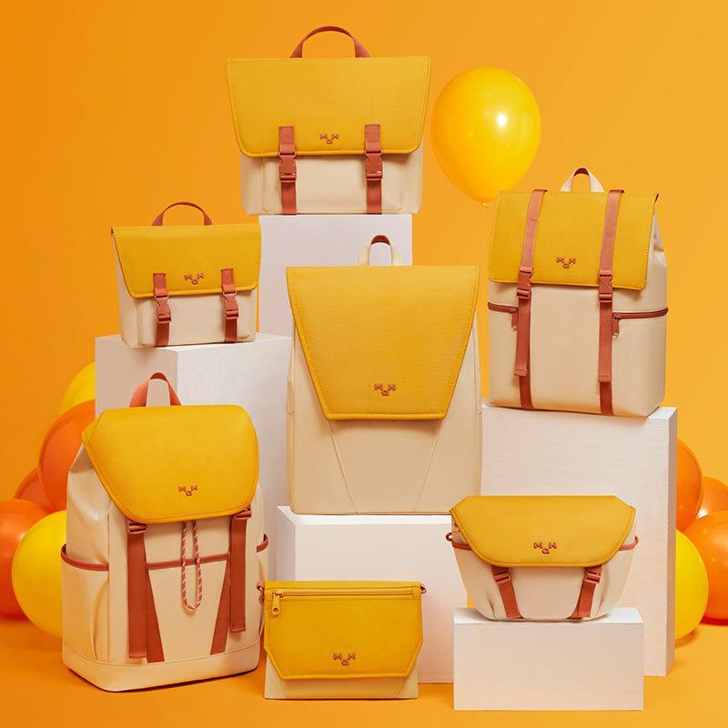 Yellow and cream backpacks, bags, and accessories displayed on white blocks with balloons, ideal for everyday use.