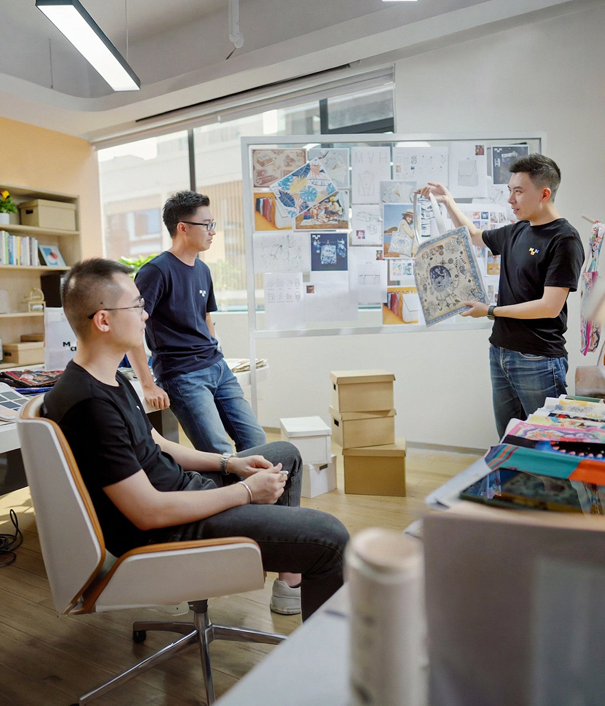 Design team reviewing patterned tote bag in modern office with mood board and fabric samples