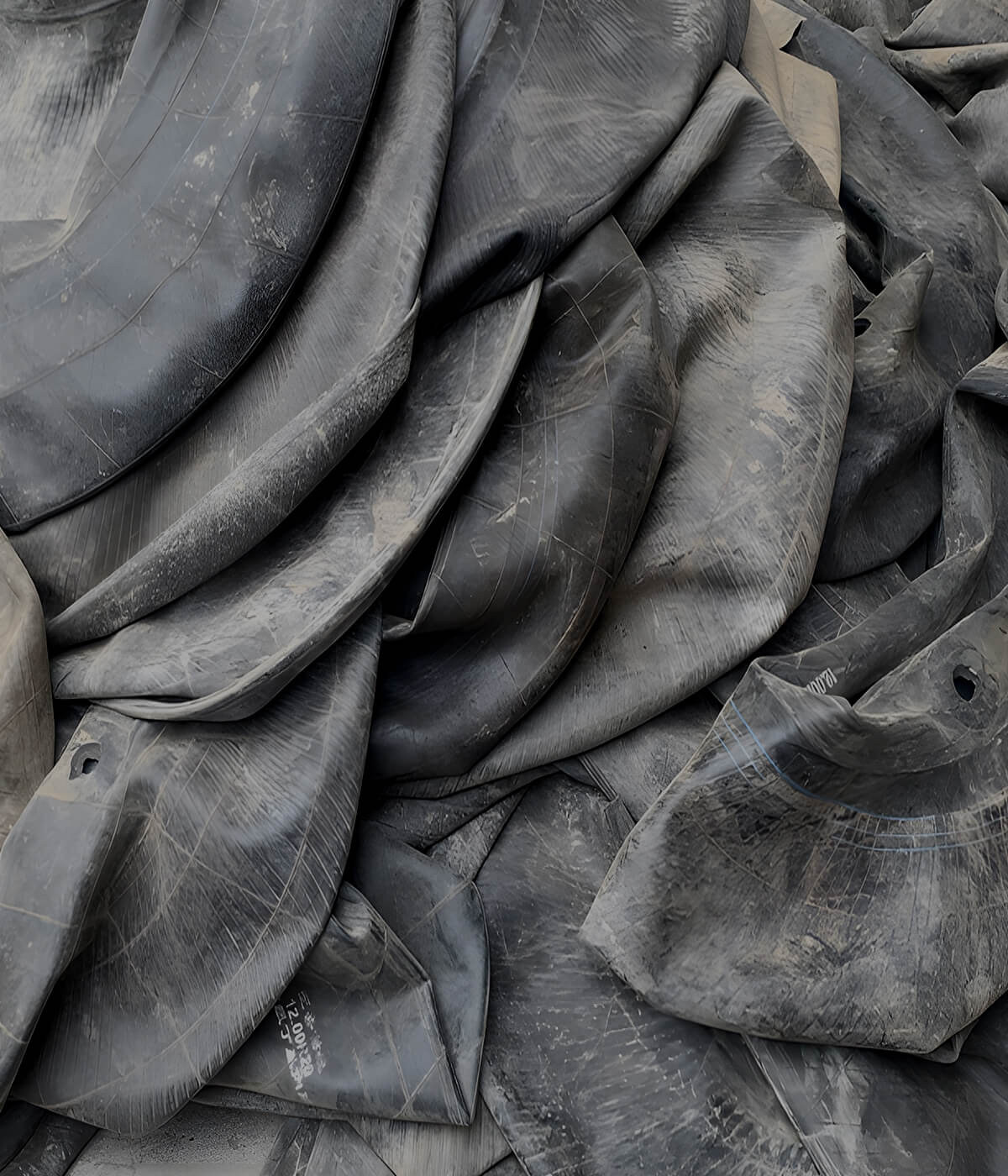 Pile of used black rubber inner tubes, textured and weathered, ideal for upcycled bags and accessories.