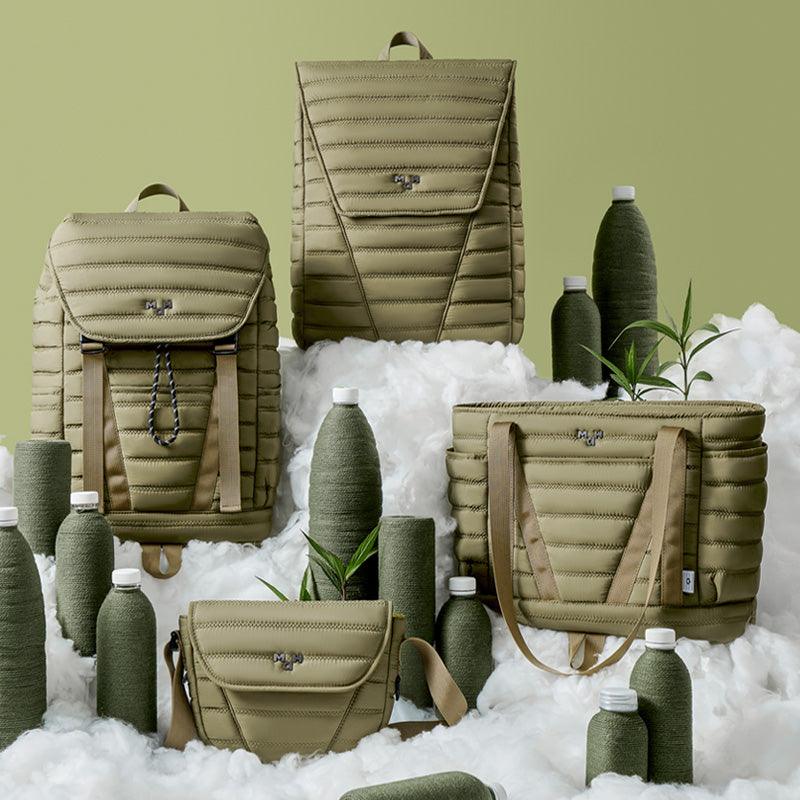 Olive green quilted backpacks, tote bag, and accessories styled with textured bottles on fluffy white base