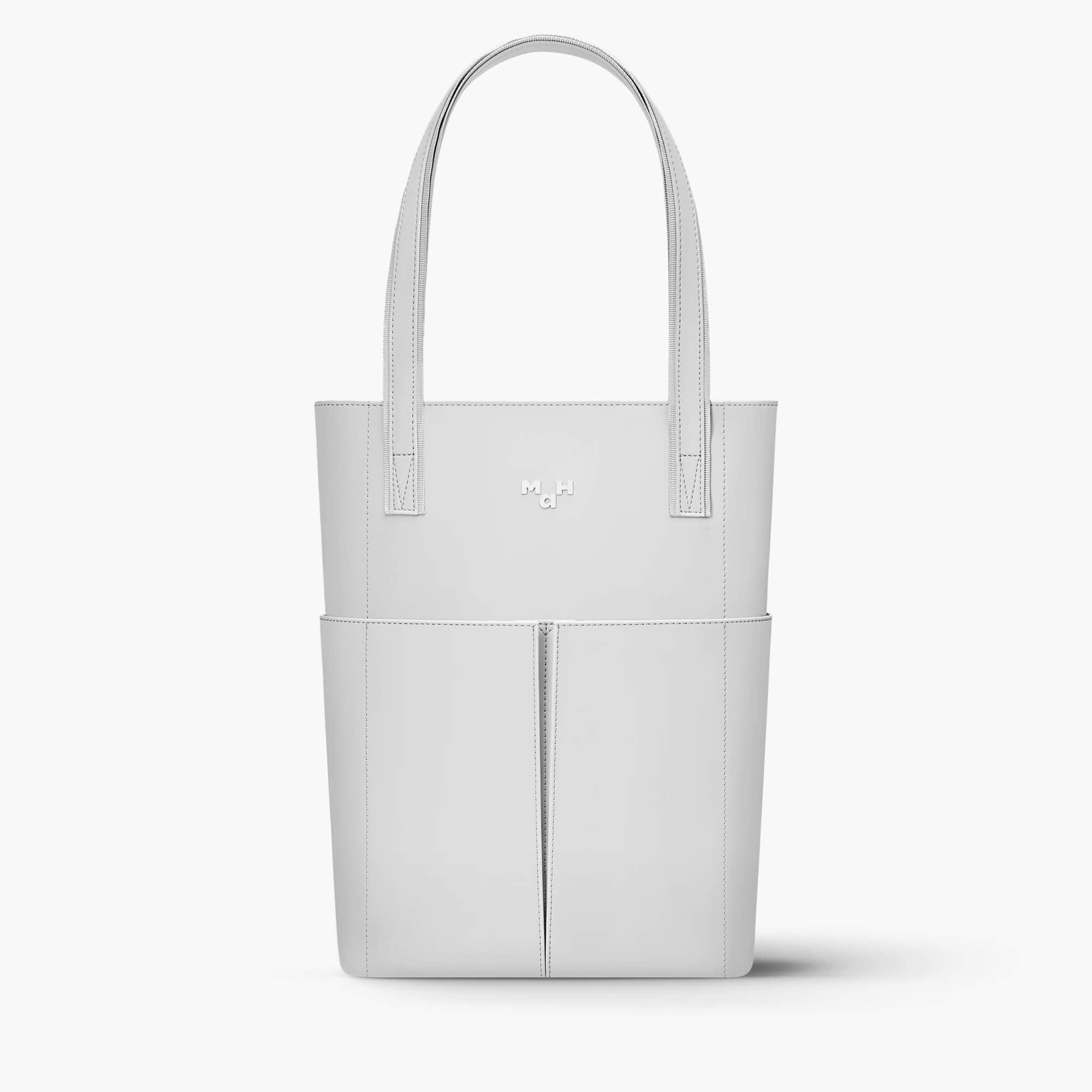 Minimalist white leather tote bag with front pockets and sleek handles, ideal for everyday use.