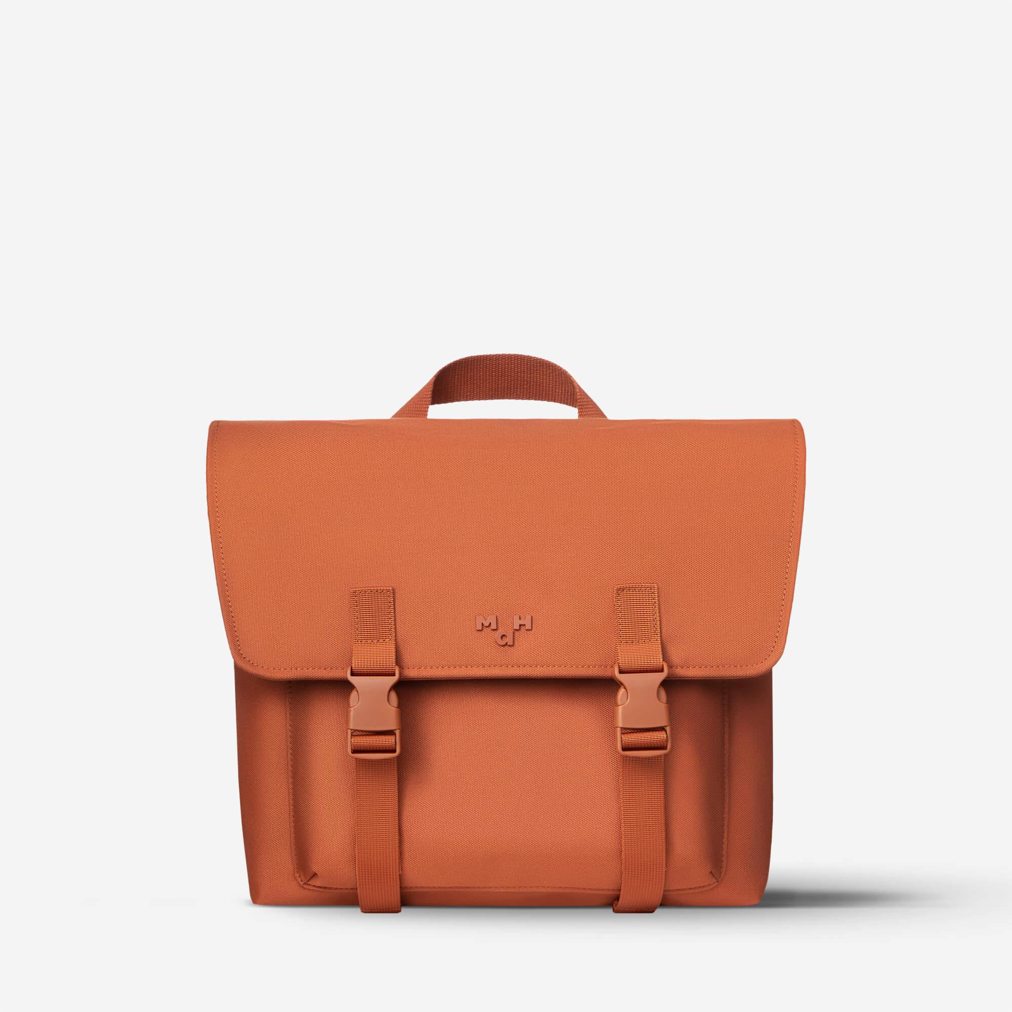 Rust orange satchel bag with front flap, buckles, and top handle for everyday carry