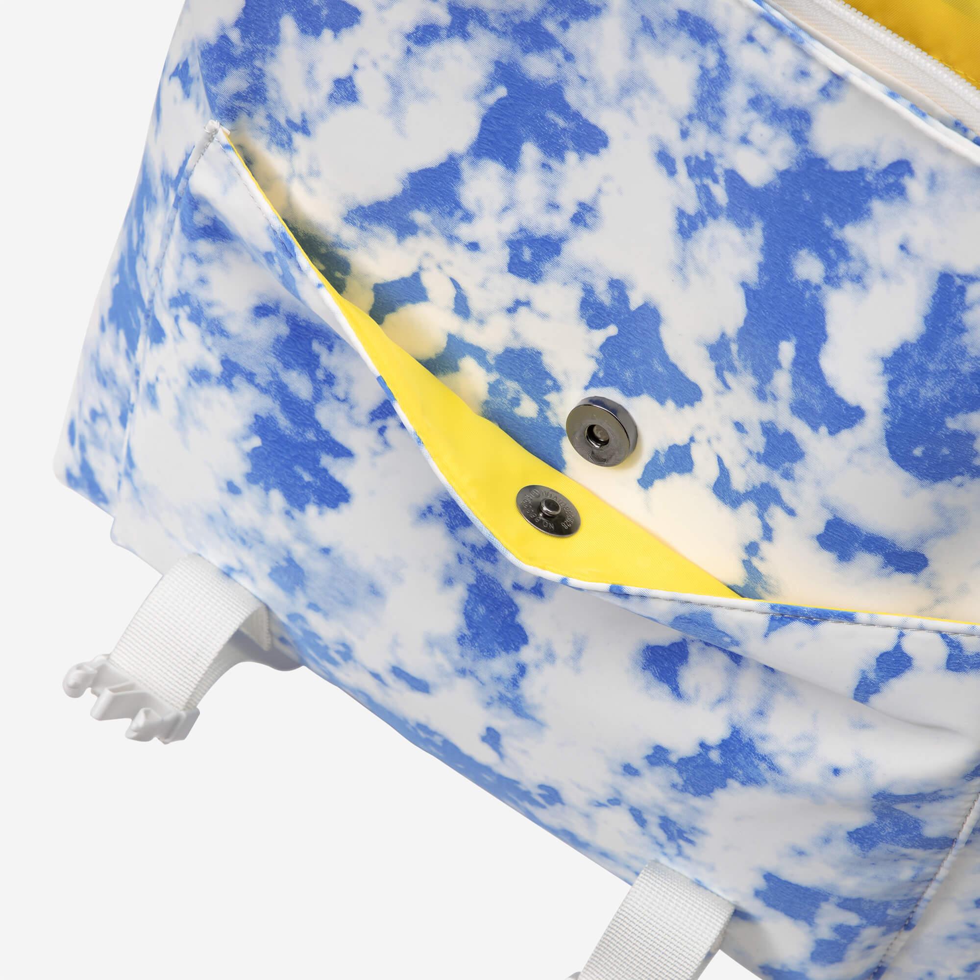 Blue and white tie-dye backpack with yellow interior and snap closure