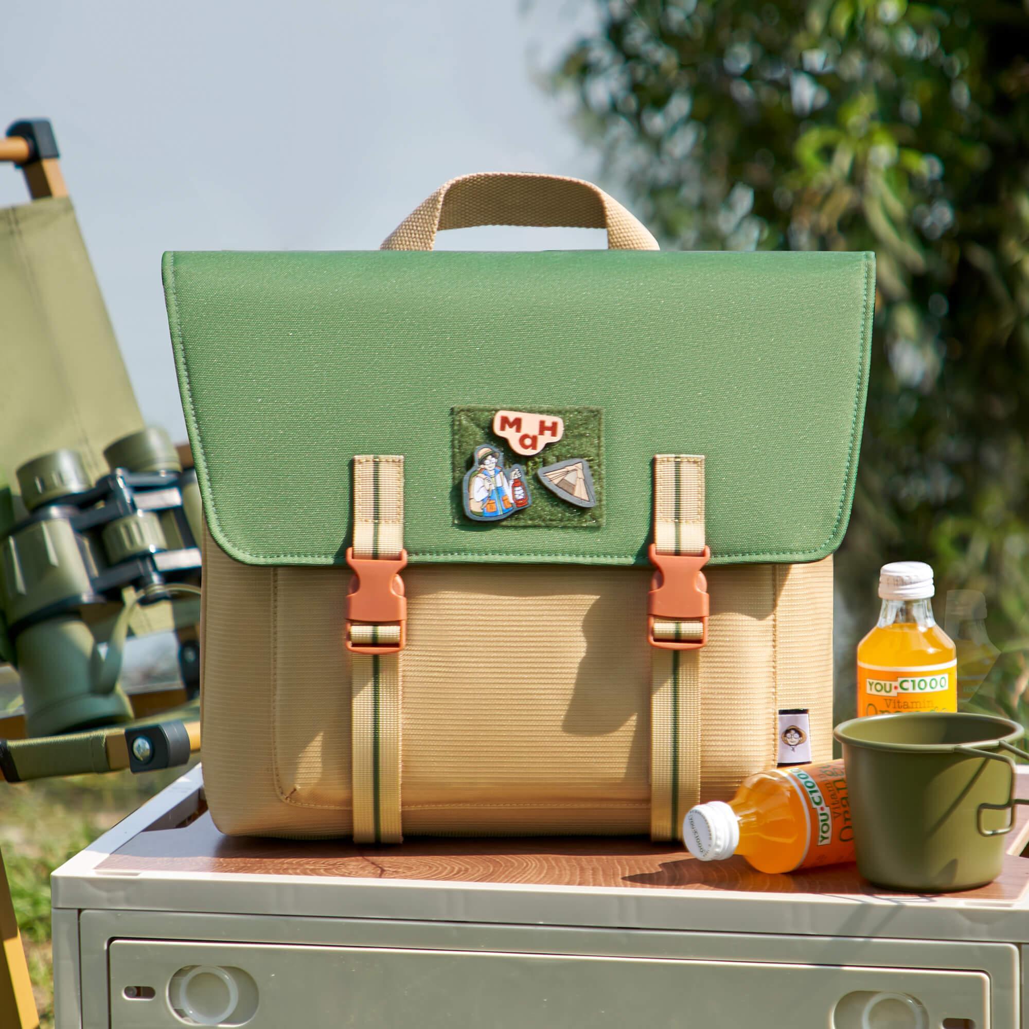 Green and beige satchel bag with patches, perfect for outdoor adventures and everyday use.