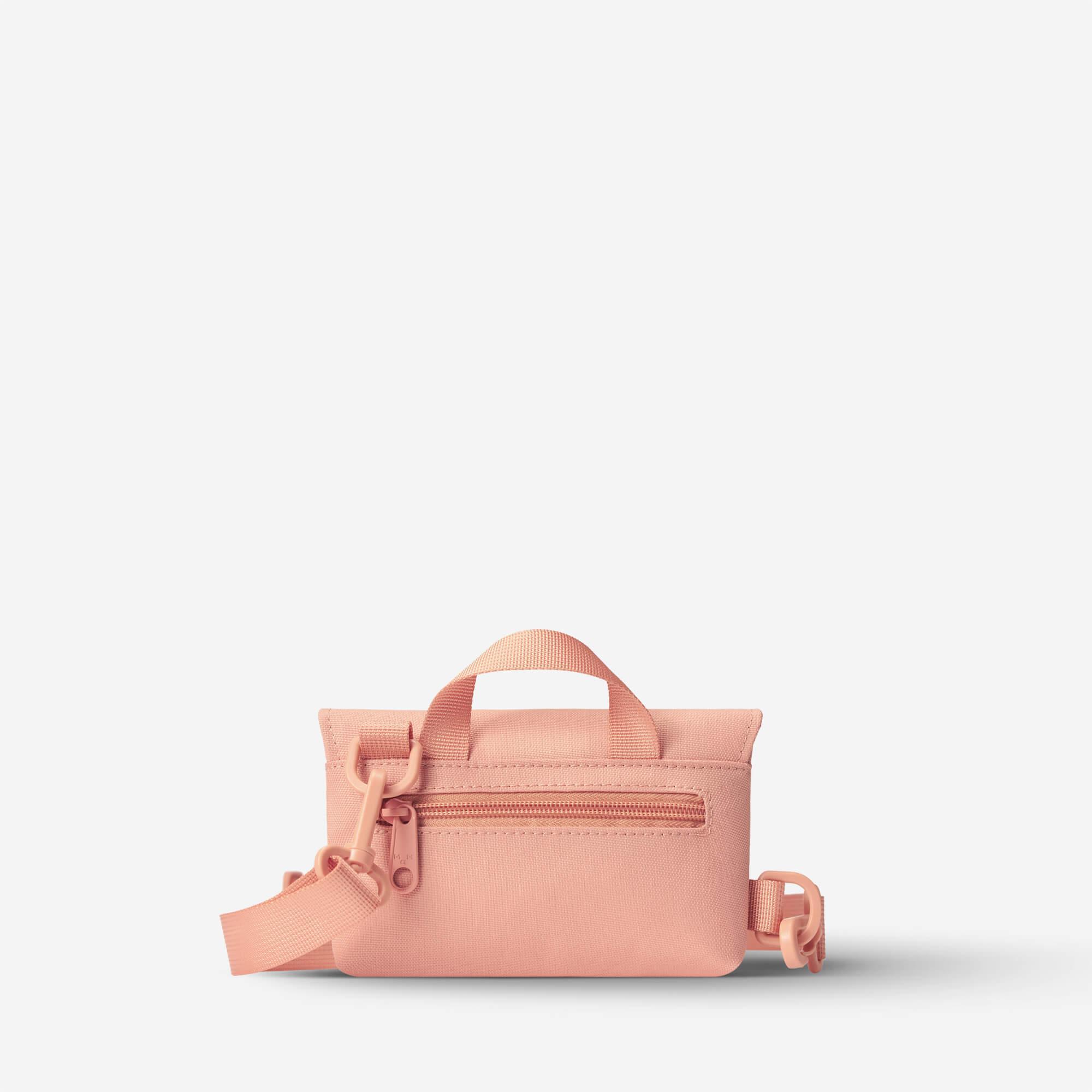 Pink compact crossbody bag with top handle and adjustable strap, ideal for everyday carry and travel essentials.