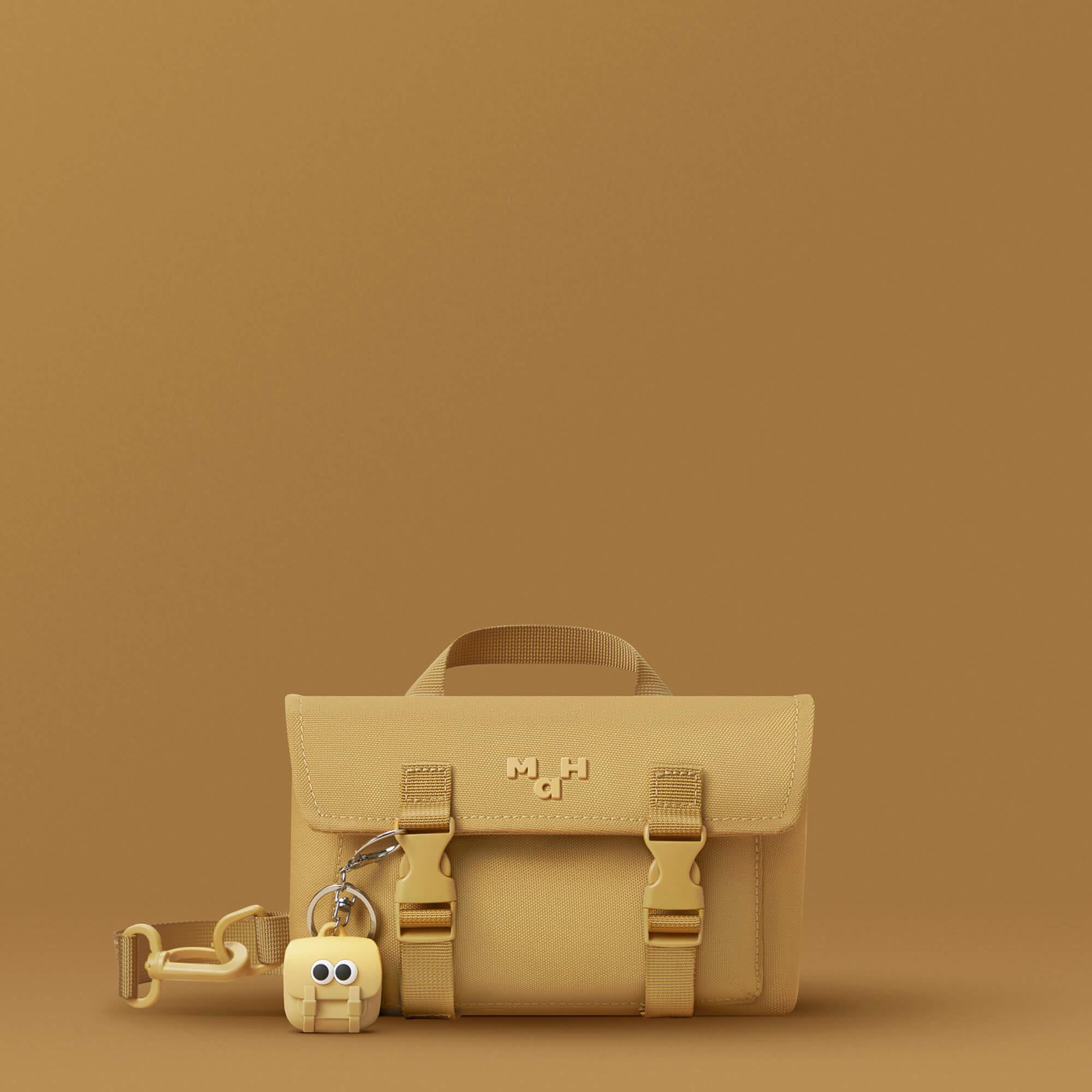 Mustard yellow satchel bag with matching keychain accessory, minimalist design for everyday use