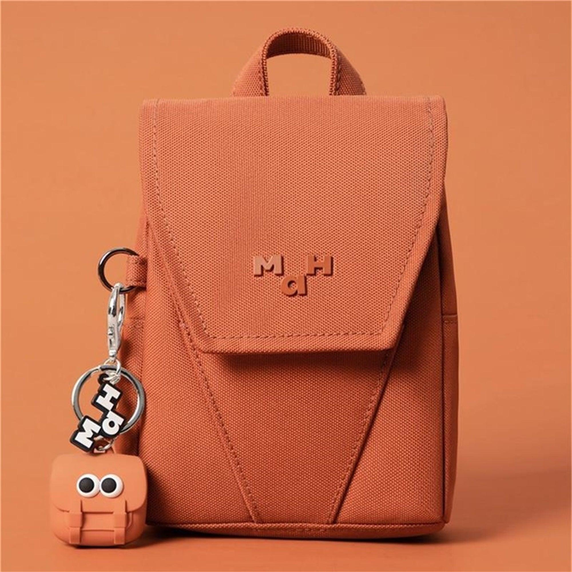 Terracotta mini backpack with flap closure and matching keychain, ideal for everyday carry and travel accessories.