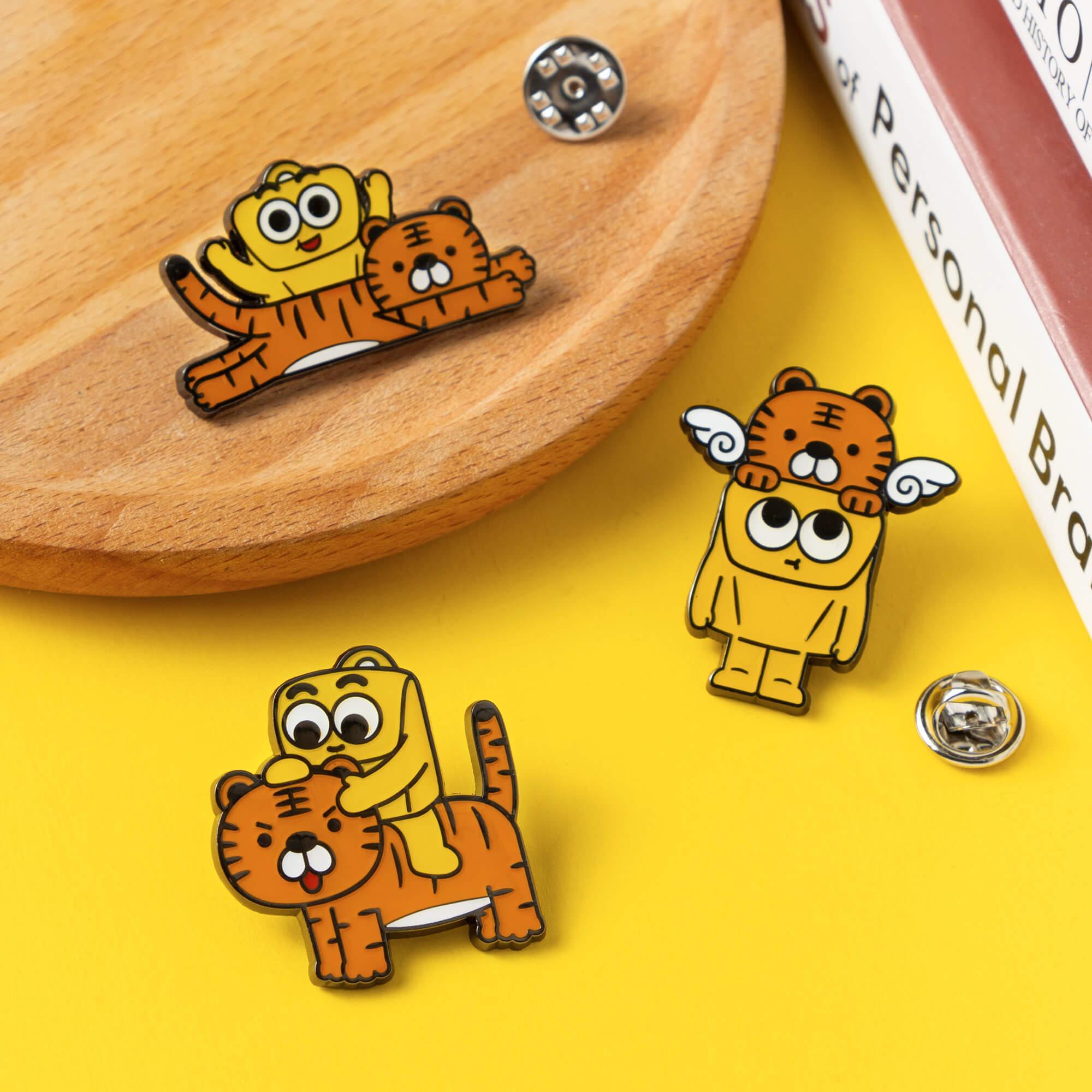 Cute cartoon tiger and bear enamel pins on wood and yellow background, fun accessory design