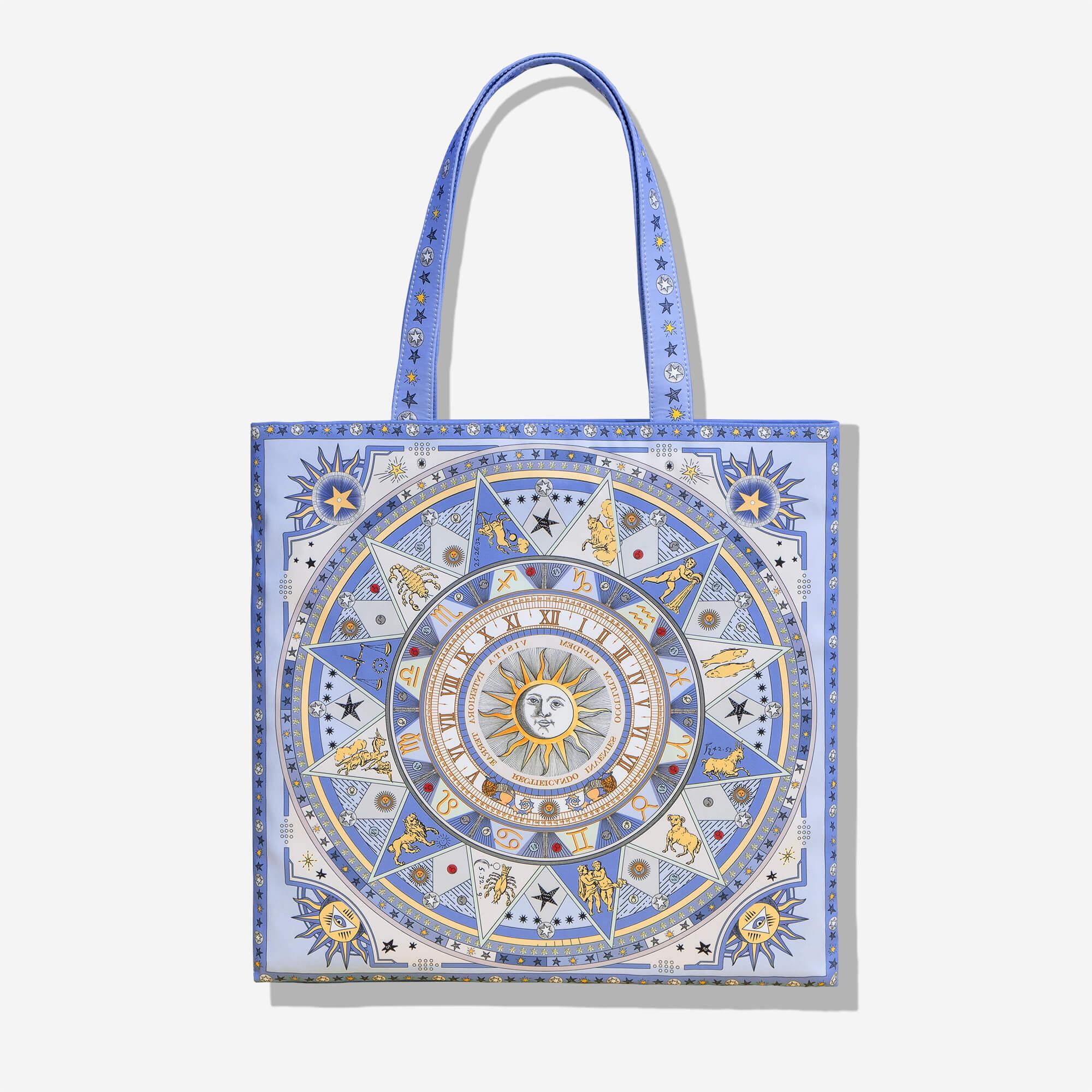 Blue tote bag with astrological zodiac design, sun motif, and star patterns for everyday carry