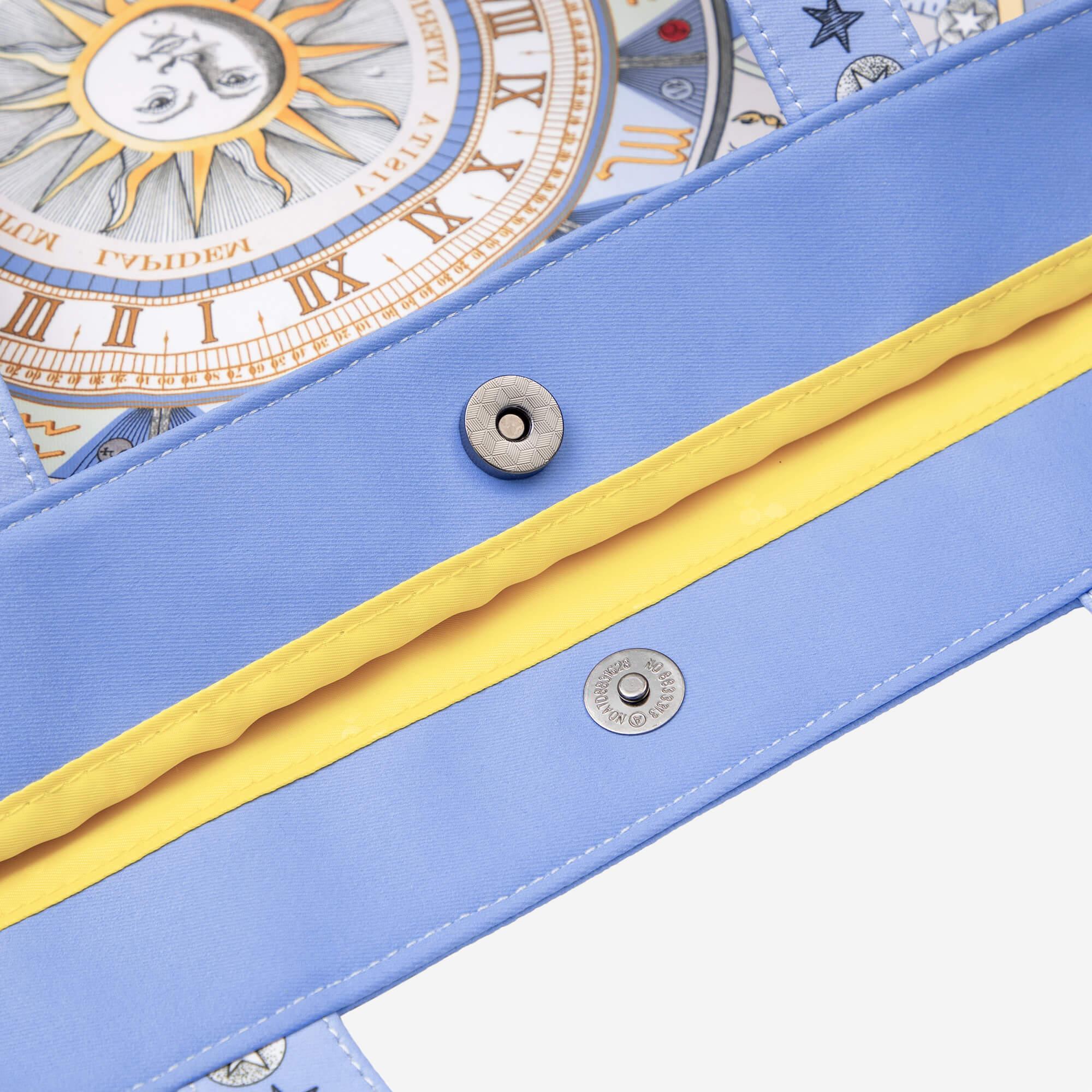 Blue bag with sun, moon, and Roman numeral clock print, yellow zipper, and snap buttons
