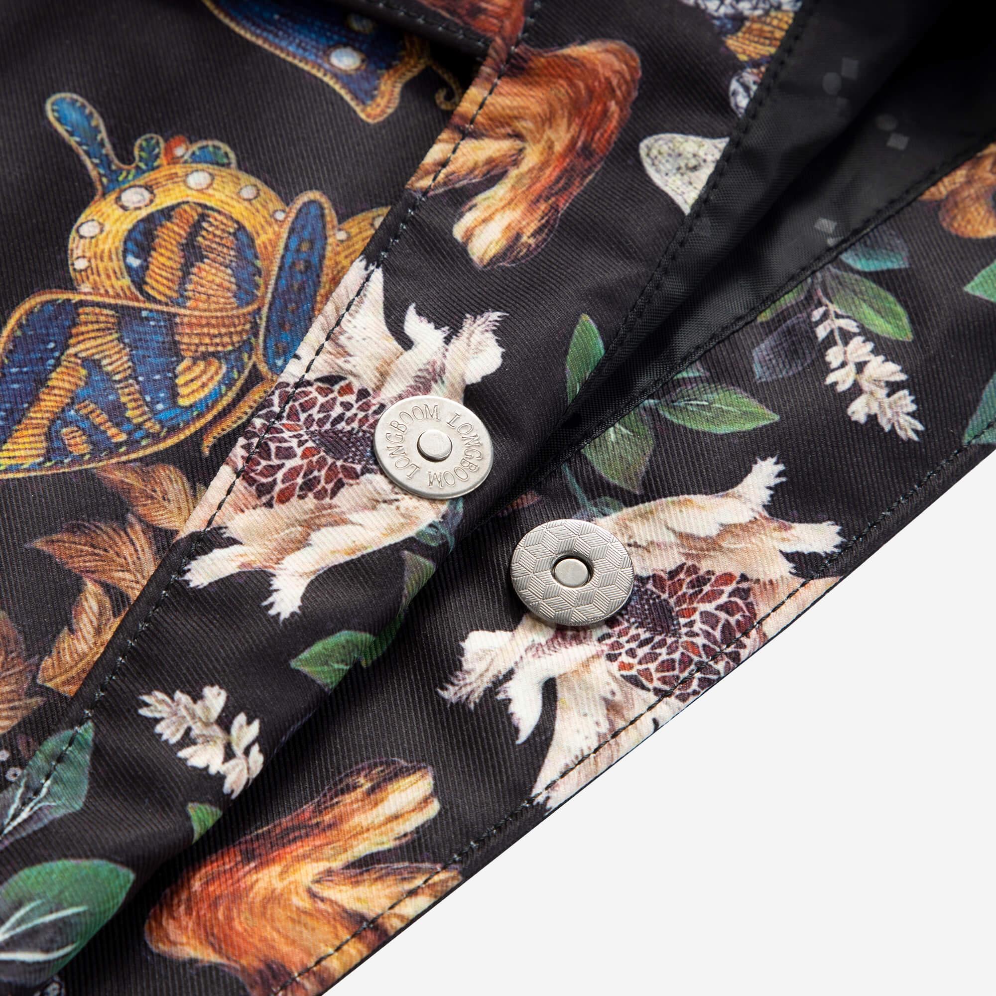 Floral and butterfly patterned fabric with metallic buttons on a black garment