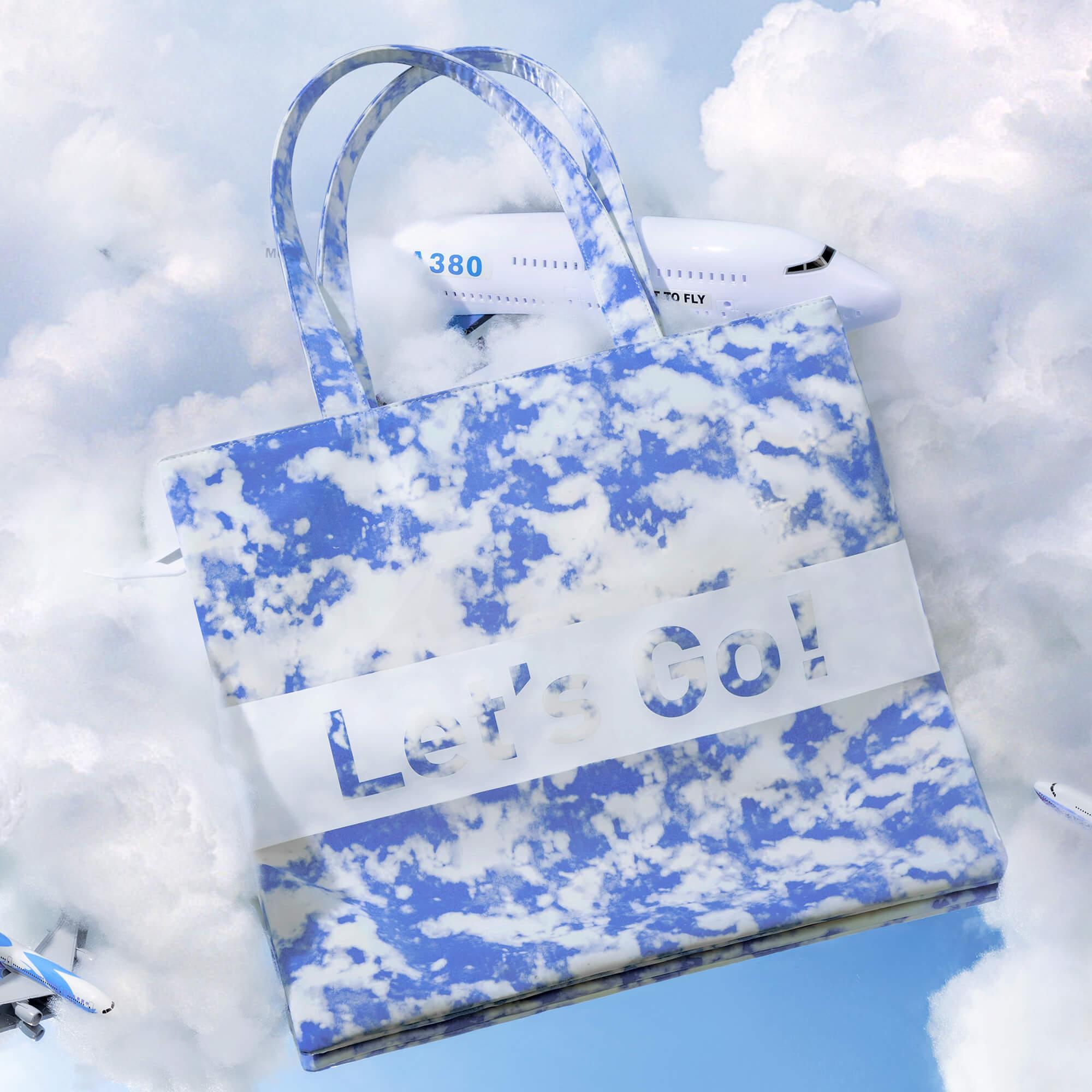 Cloud-print tote bag with 'Let's Go!' text, airplane models, sky background