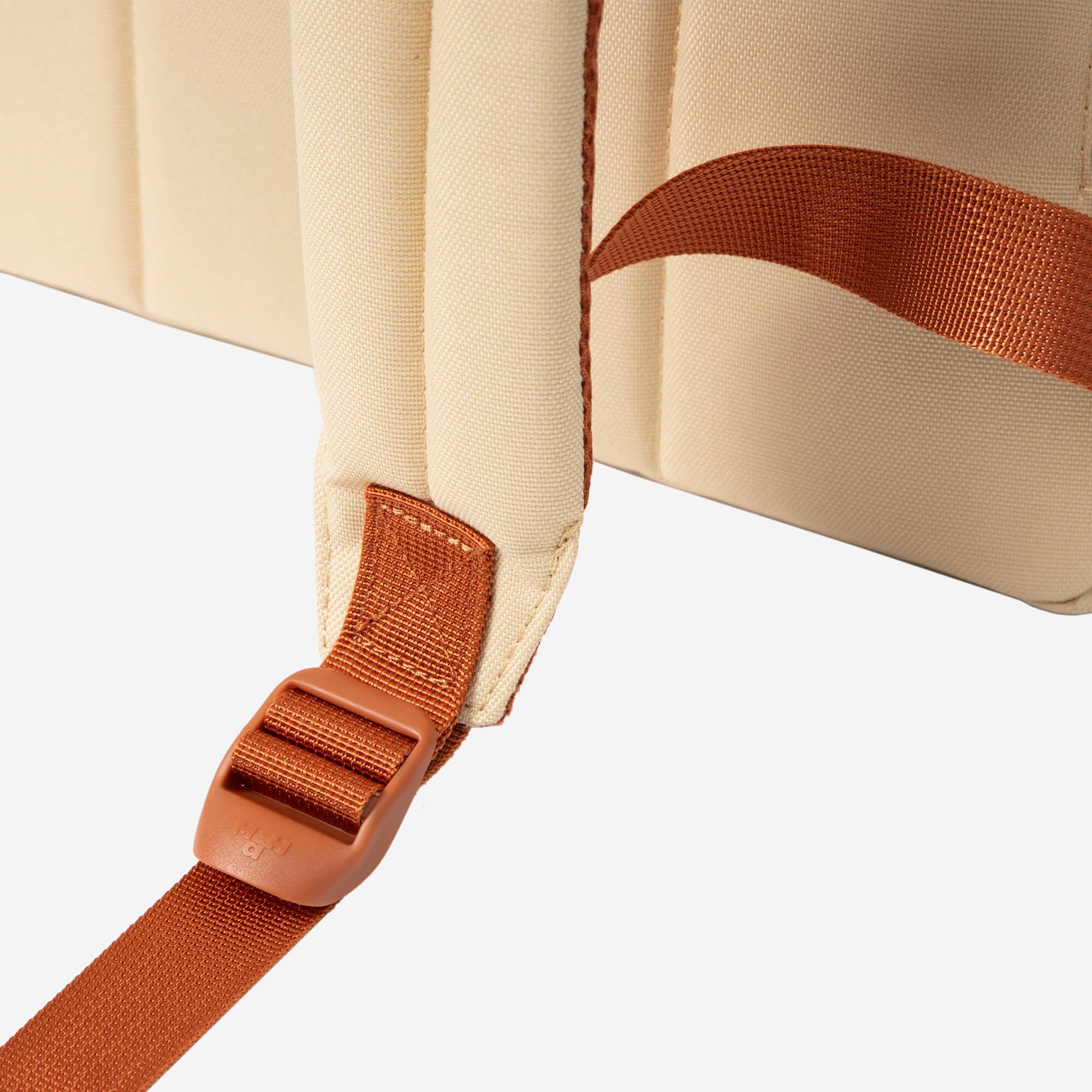 Cream canvas backpack with rust-colored adjustable straps and buckle detail