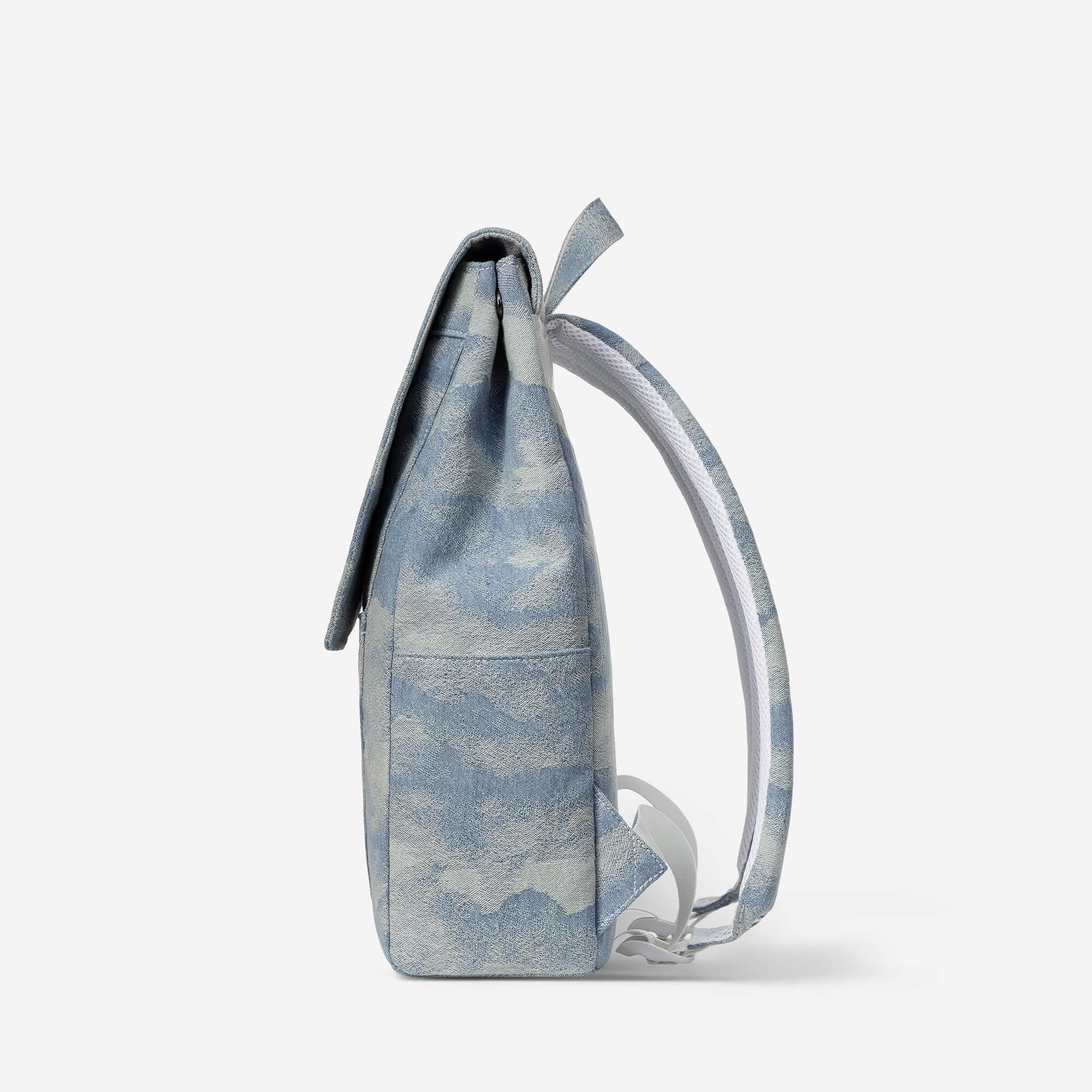Blue tie-dye backpack with white padded straps, side view on white background