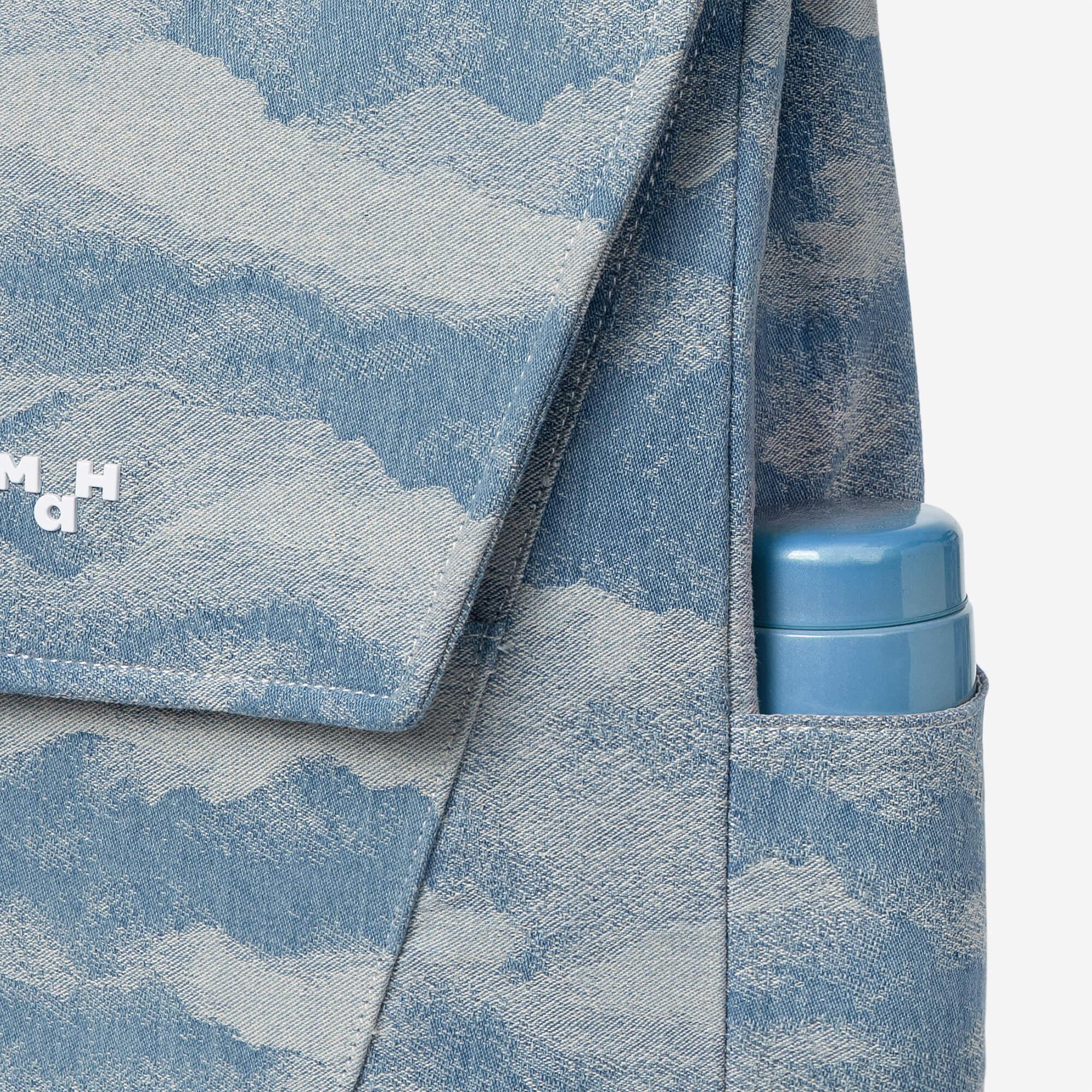 Blue denim backpack with cloud print, side pocket holding water bottle, stylish everyday carry