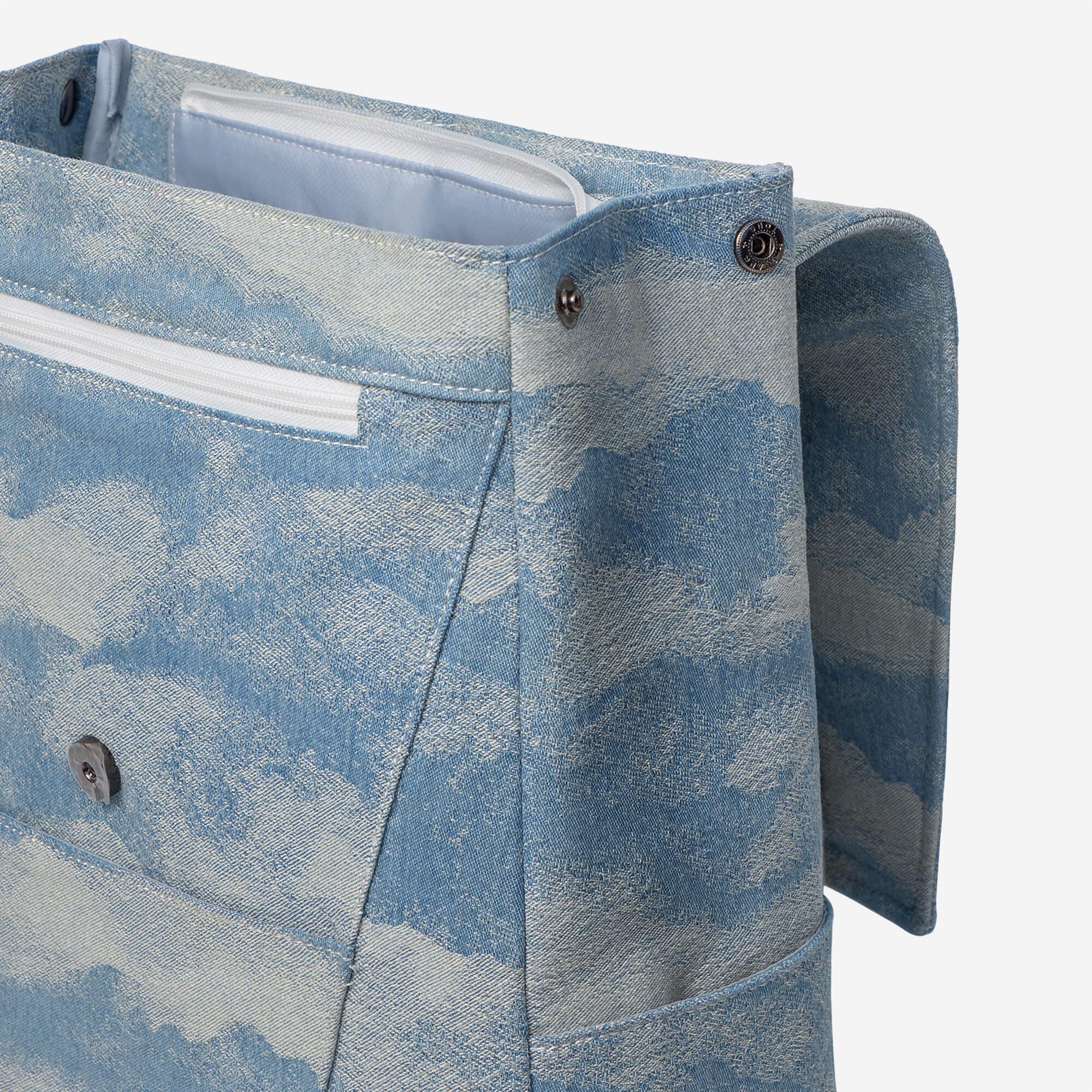 Blue denim tote bag with cloud print, zip pocket, and metal hardware details
