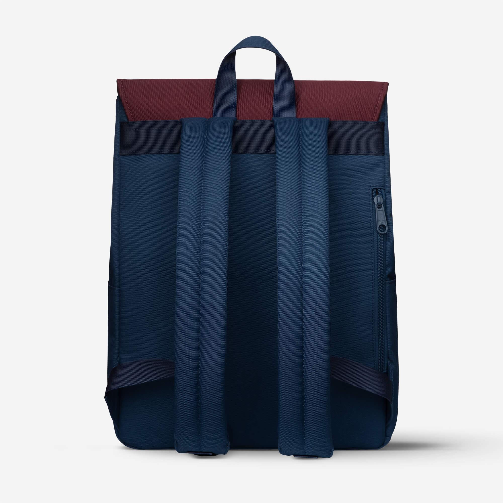 Navy blue backpack with burgundy top panel, padded straps, and side zipper pocket for daily use