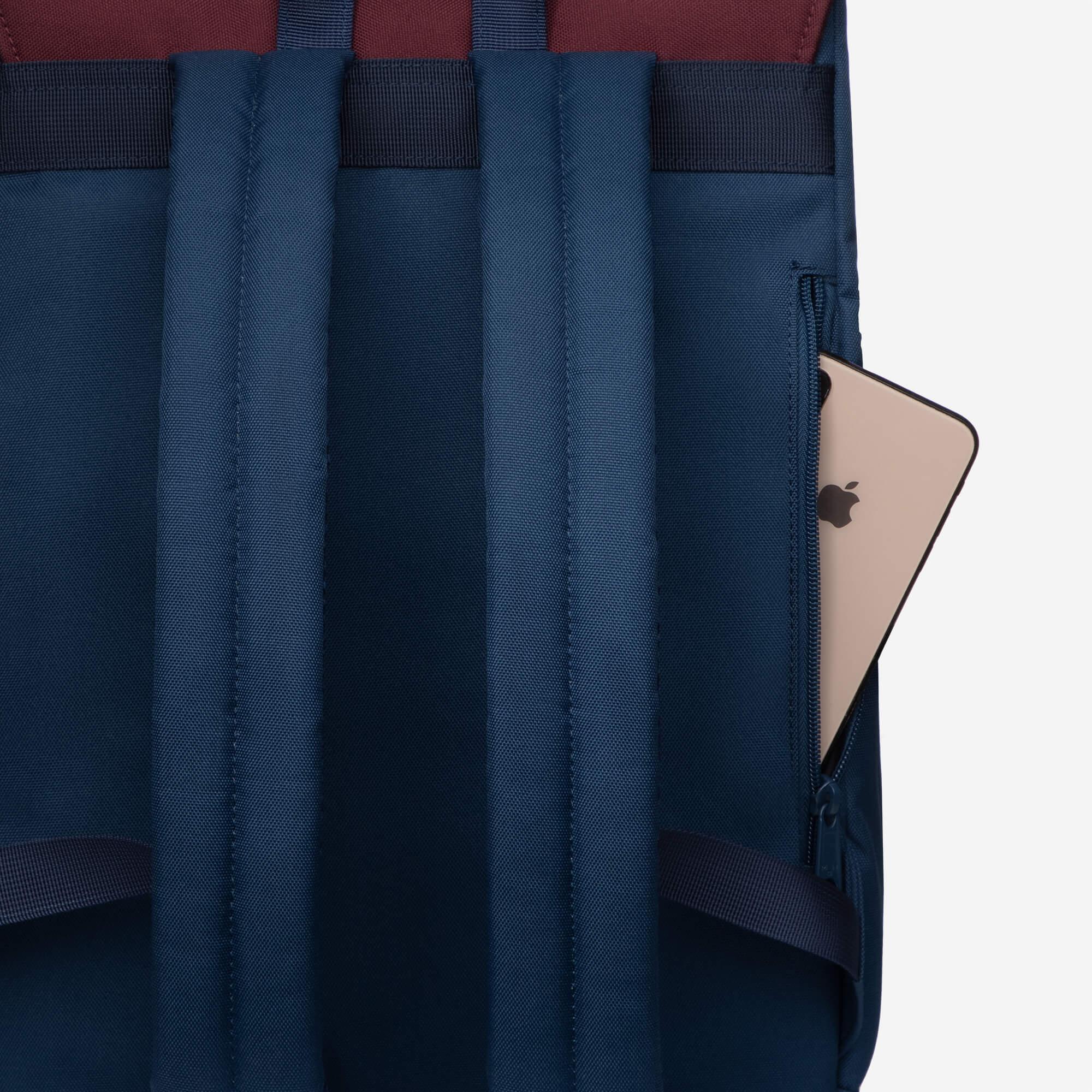 Navy blue backpack with padded straps and side pocket holding a tablet, ideal for daily commute or school use.