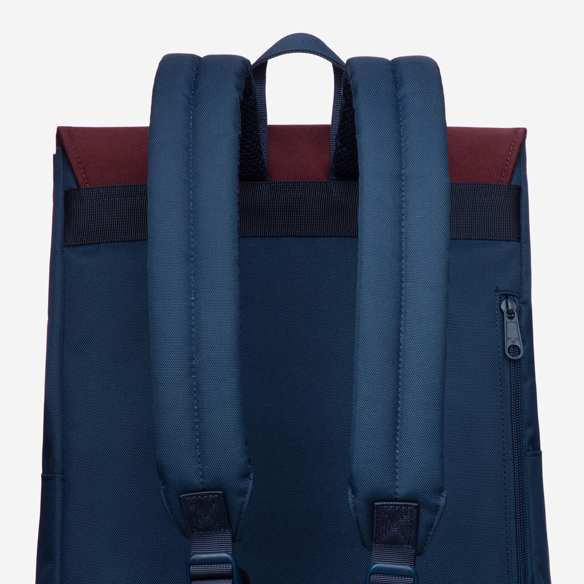 Navy blue backpack with padded shoulder straps, top handle, and burgundy accent panel