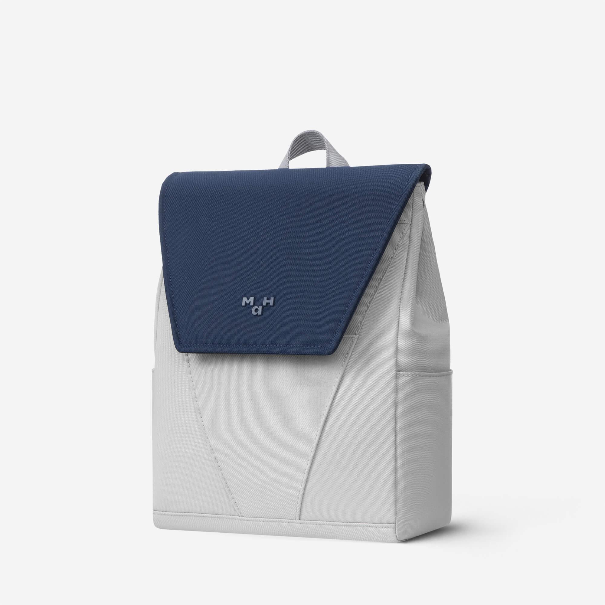Modern two-tone backpack with navy flap and gray body, featuring minimalist design and top handle