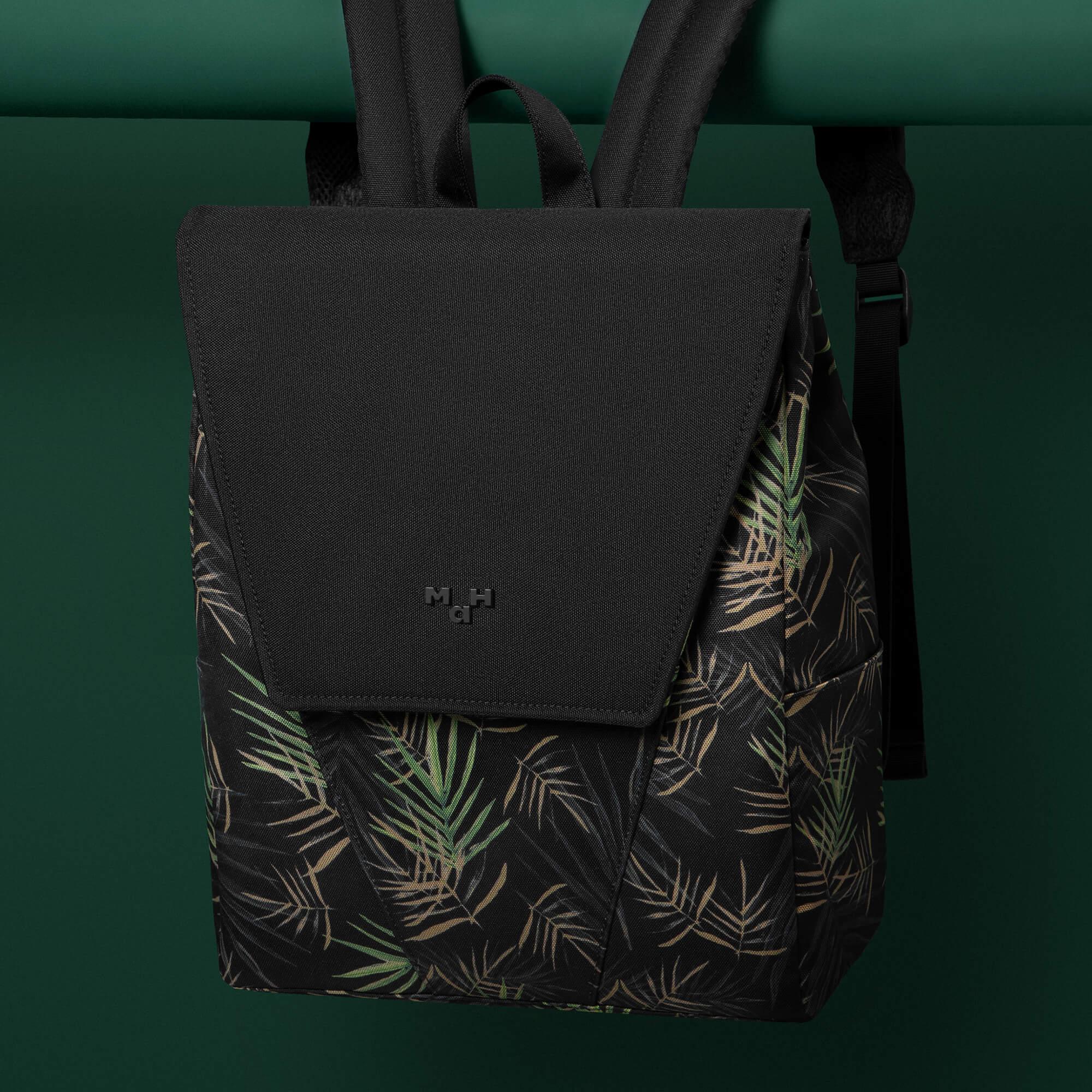 Black backpack with tropical leaf print, featuring front flap and adjustable straps, ideal for everyday use.