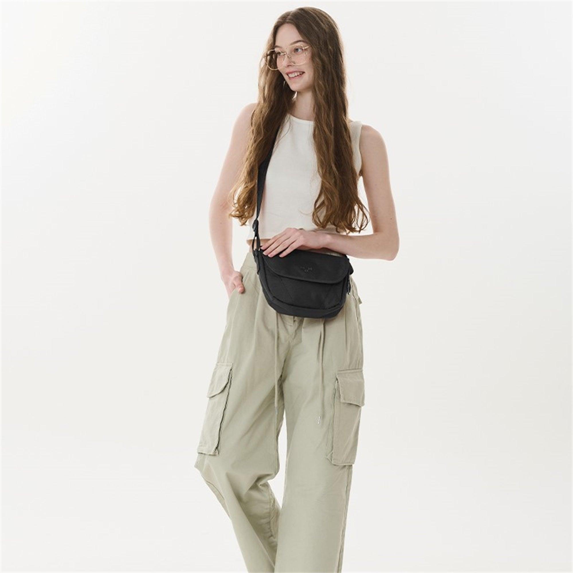 Woman wearing black crossbody bag with beige cargo pants and white top, stylish everyday accessory