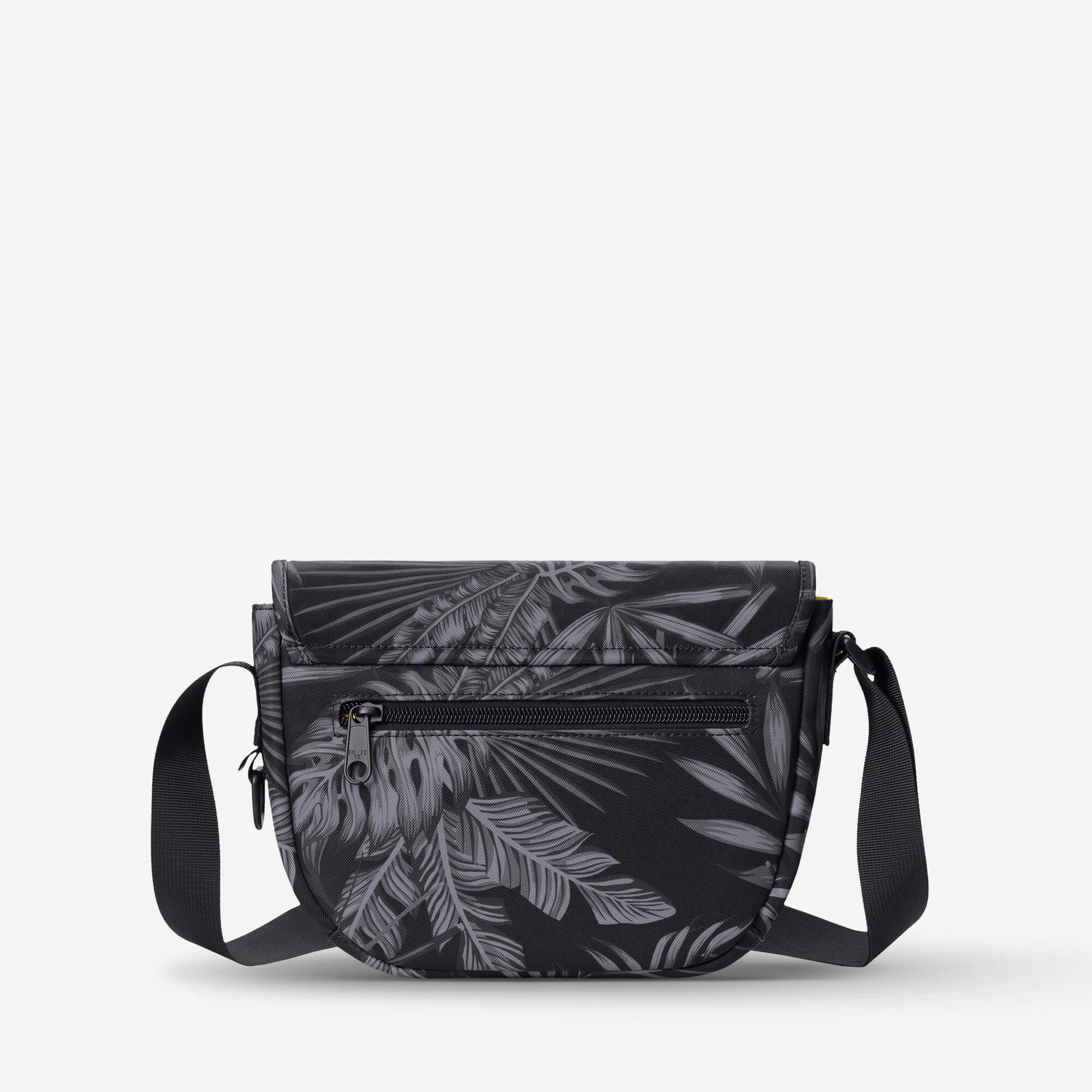 Black crossbody bag with gray tropical leaf print, adjustable strap, front zipper pocket