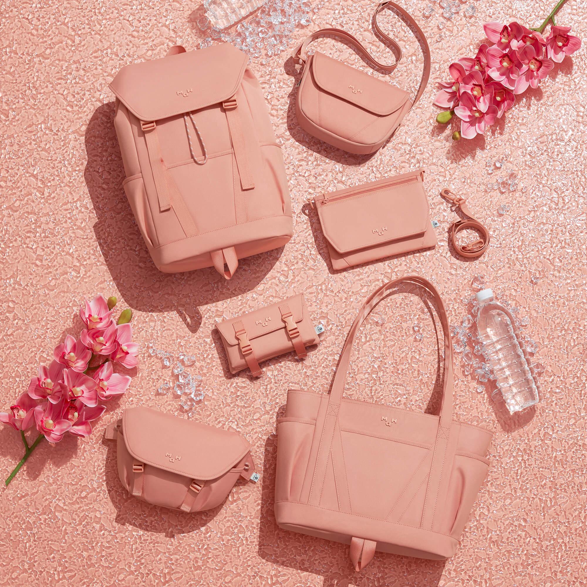 Pink backpack, tote, crossbody, and wallet set with orchids on textured surface